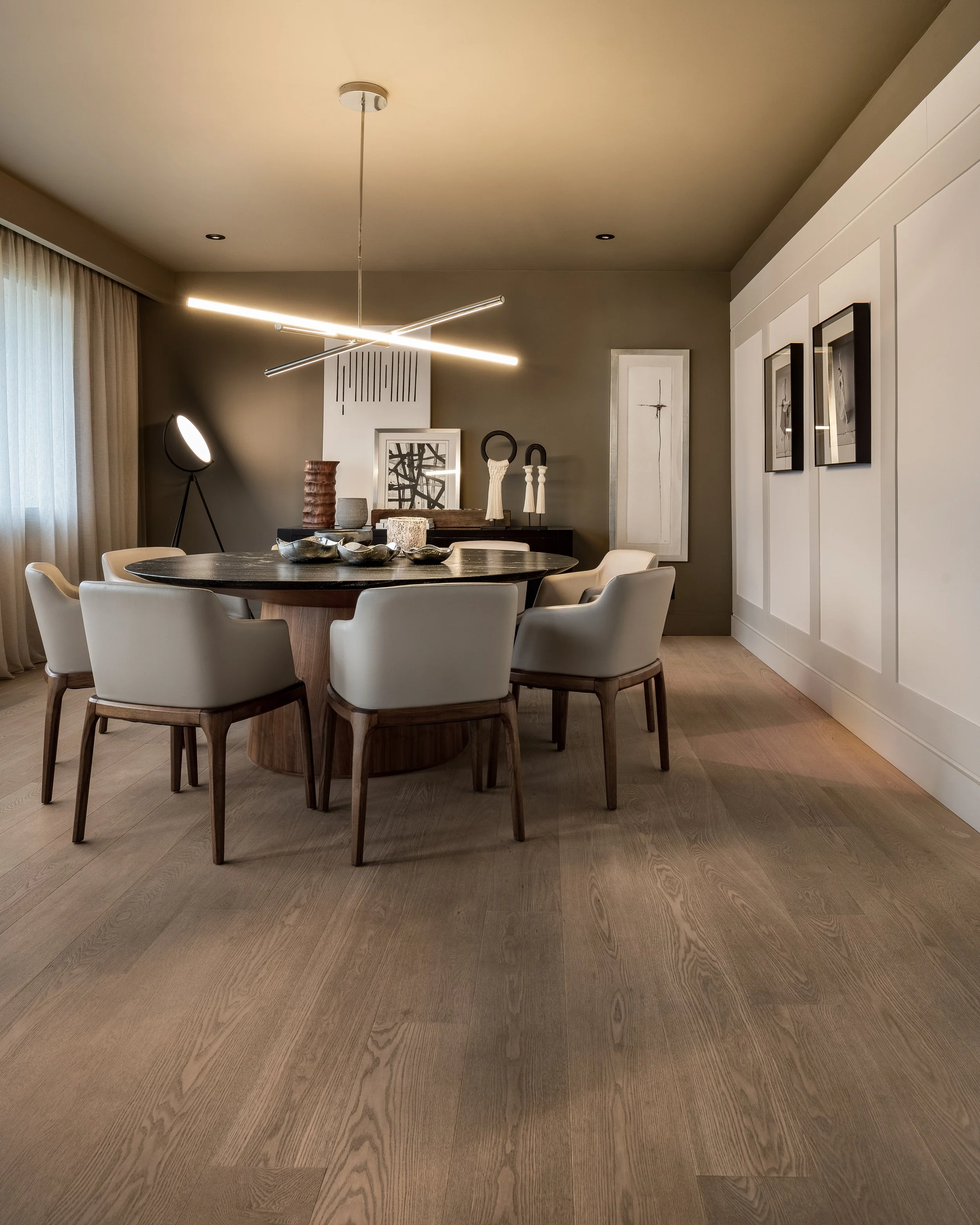Sala de comedor moderna con mesa redonda, sillas blancas, decoraciones y lámpara de techo
