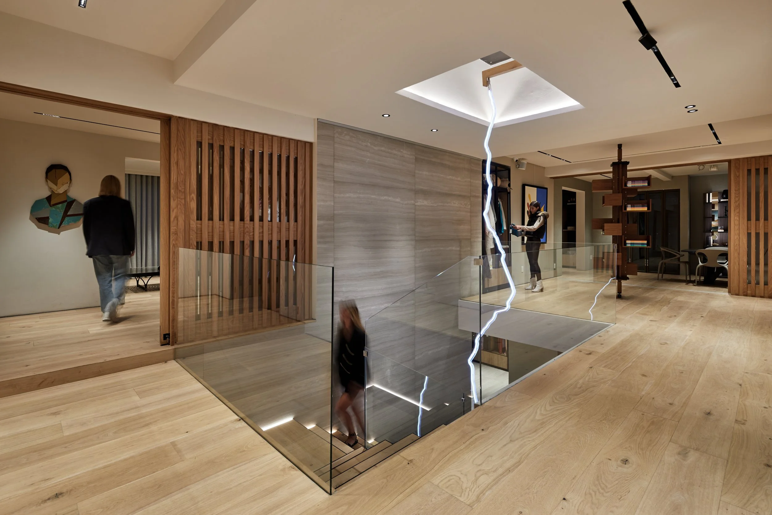 Interior moderno con escaleras de vidrio, paredes de madera y decoración artística