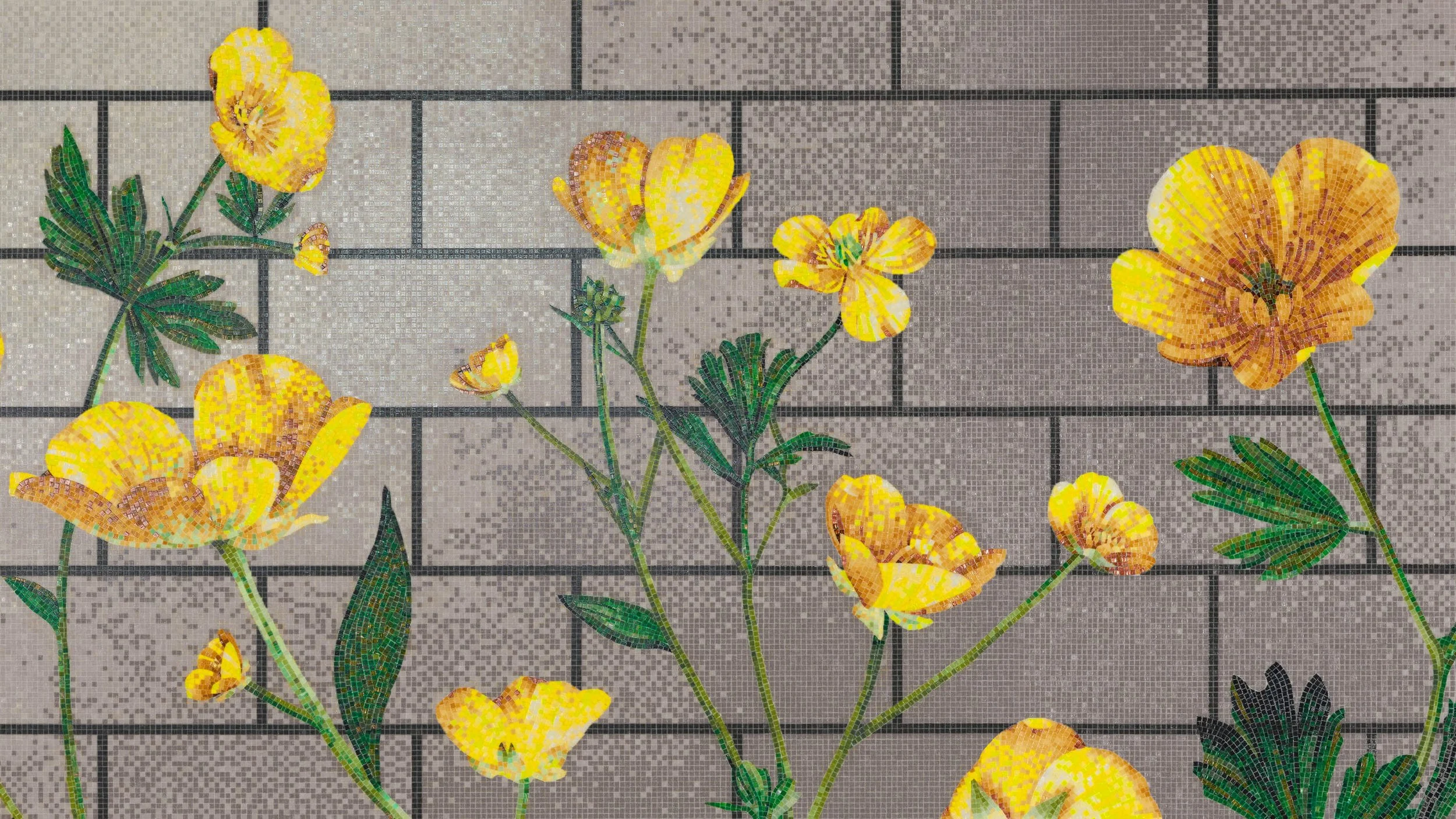 Mosaico de flores amarillas y verdes en un muro de ladrillos grises.