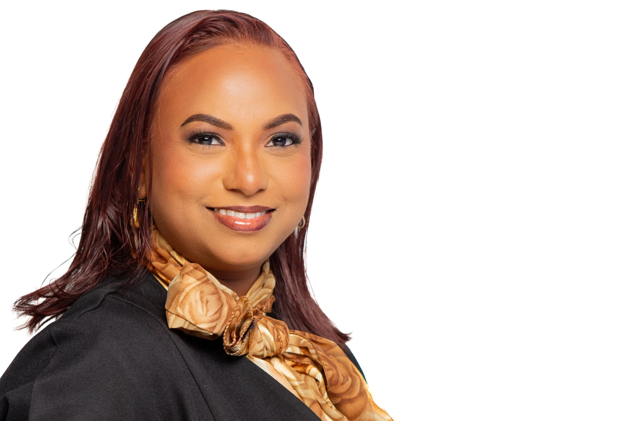 Professional woman with red hair, wearing a black blazer and a beige scarf, smiling at the camera.