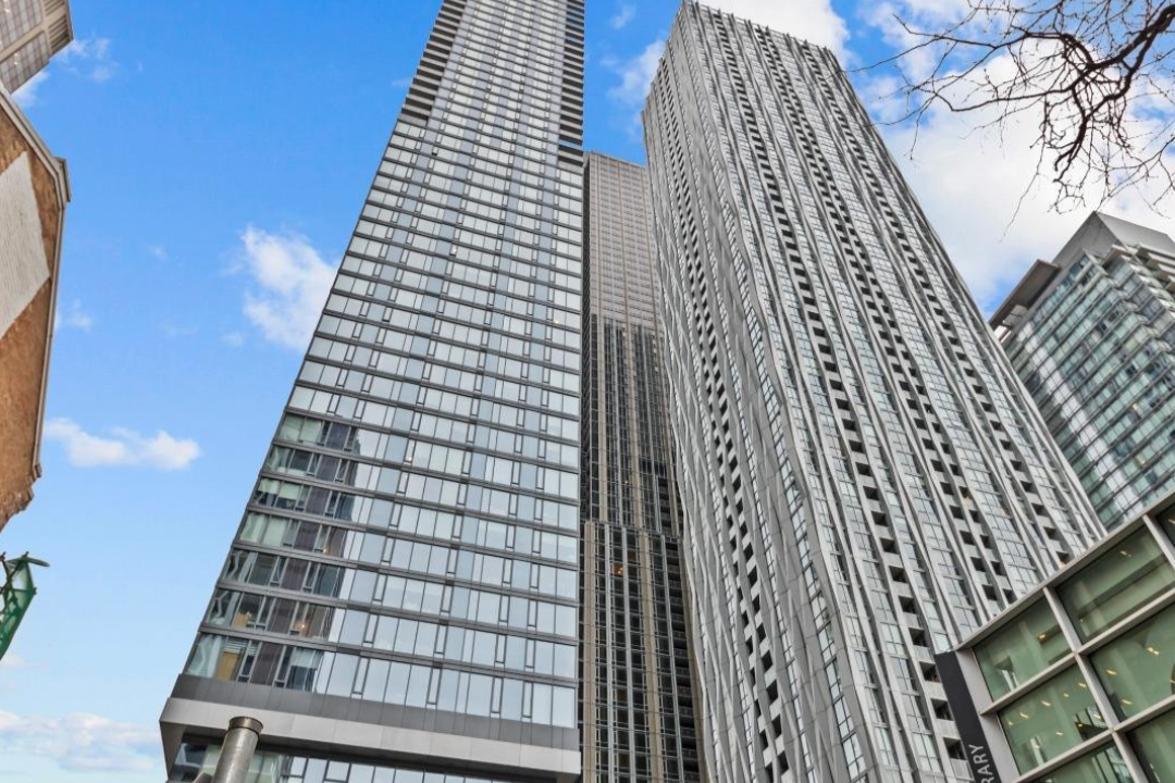Low-angle view of tall modern skyscrapers with glass facades and a partly cloudy sky in the background.