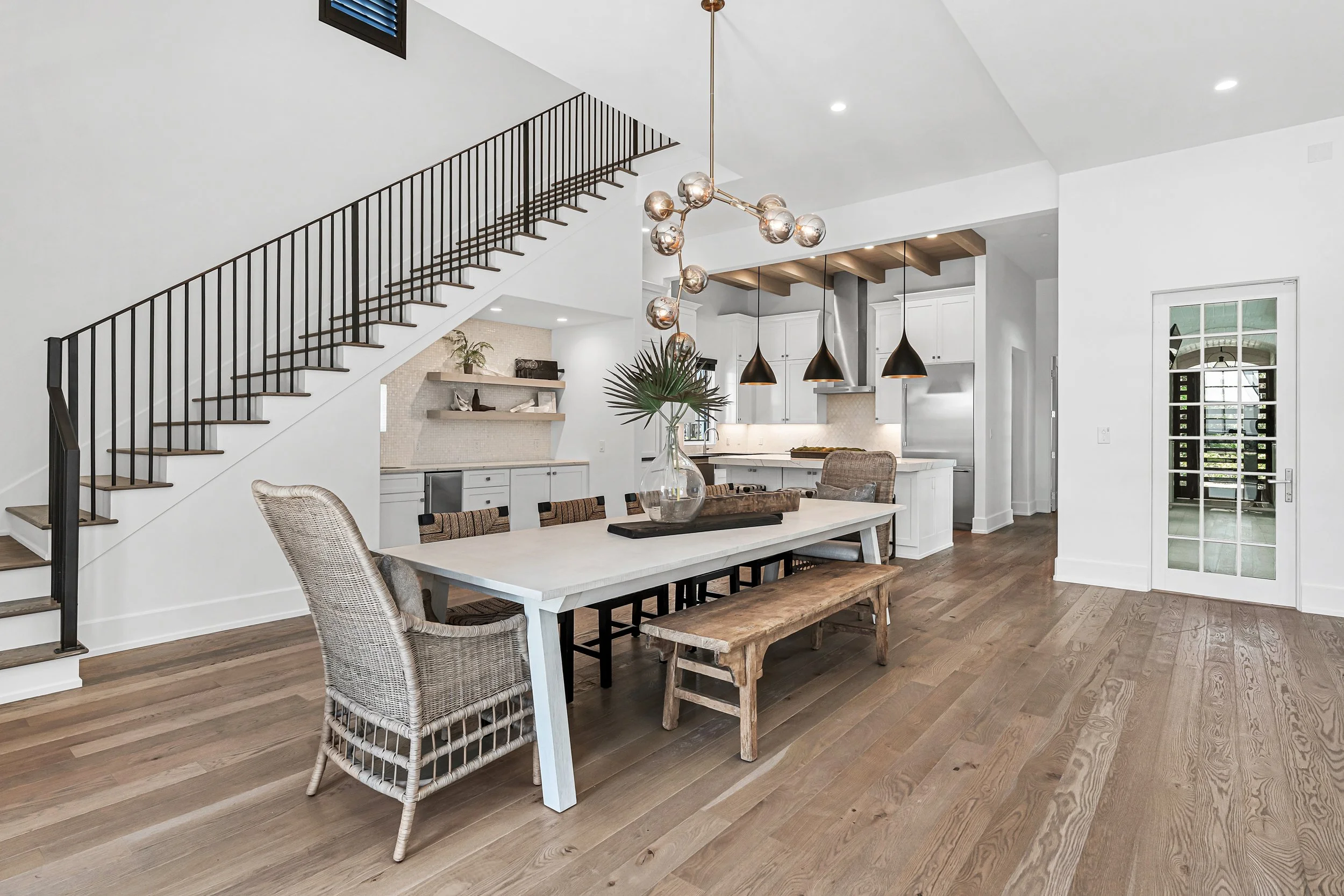 Open-concept dining and kitchen area with wooden flooring, white walls, and modern decor. - Real estate photography in 30A, Destin, and Panama City Beach by Matt Jozwiak