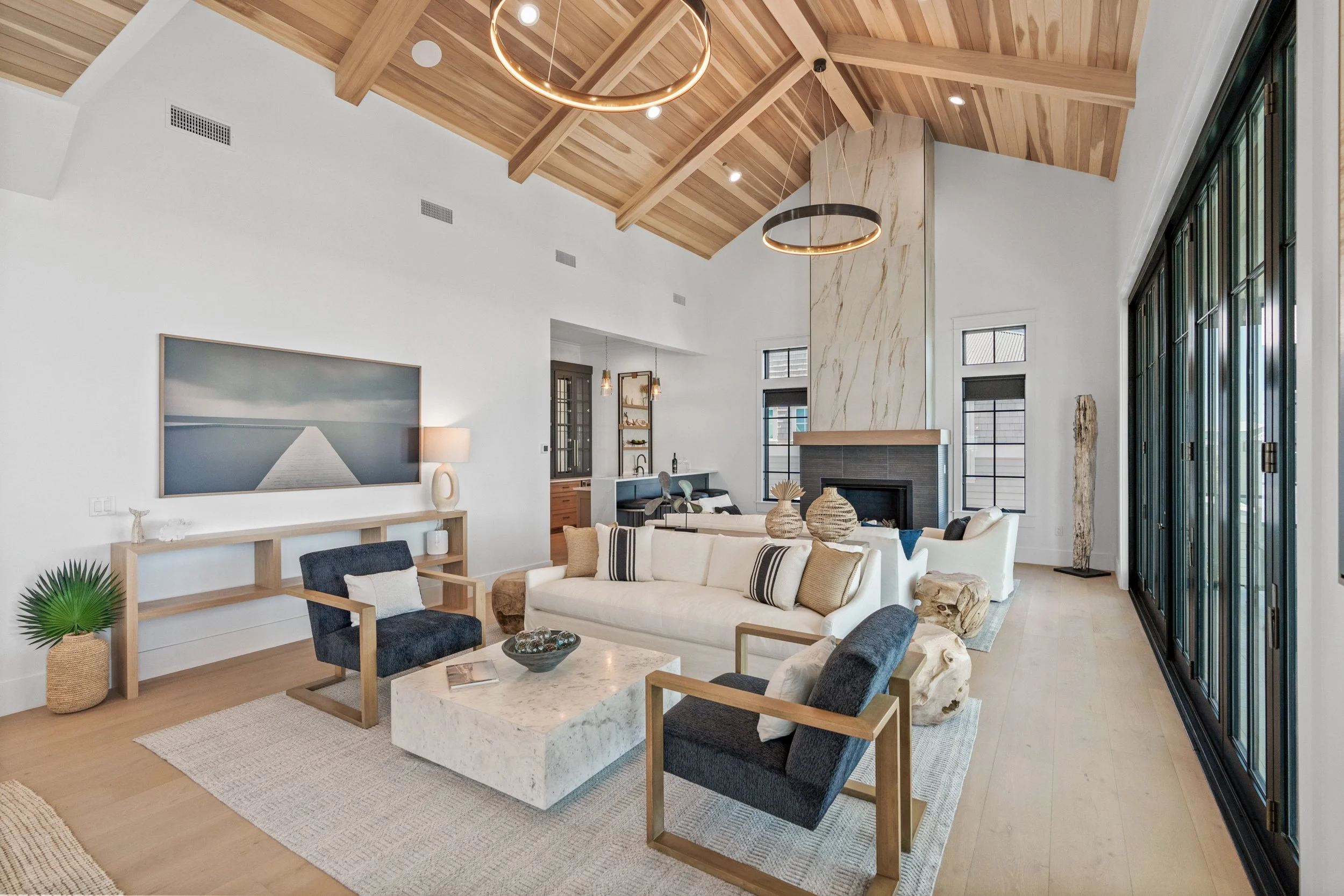A modern living room with white walls, high wooden ceiling, and large black-framed glass doors - Real estate photography in 30A, Destin, and Panama City Beach by Matt Jozwiak