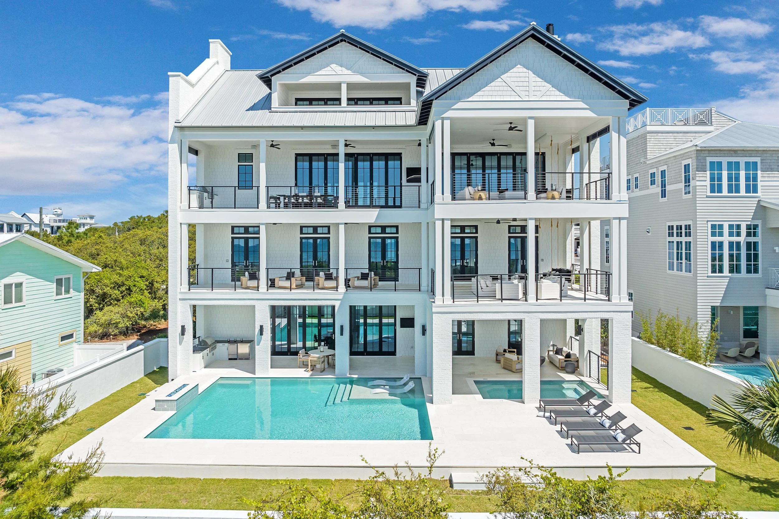 Large modern white house with multiple balconies, a swimming pool, and outdoor lounge areas on a sunny day - Real estate photography in 30A, Destin, and Panama City Beach by Matt Jozwiak