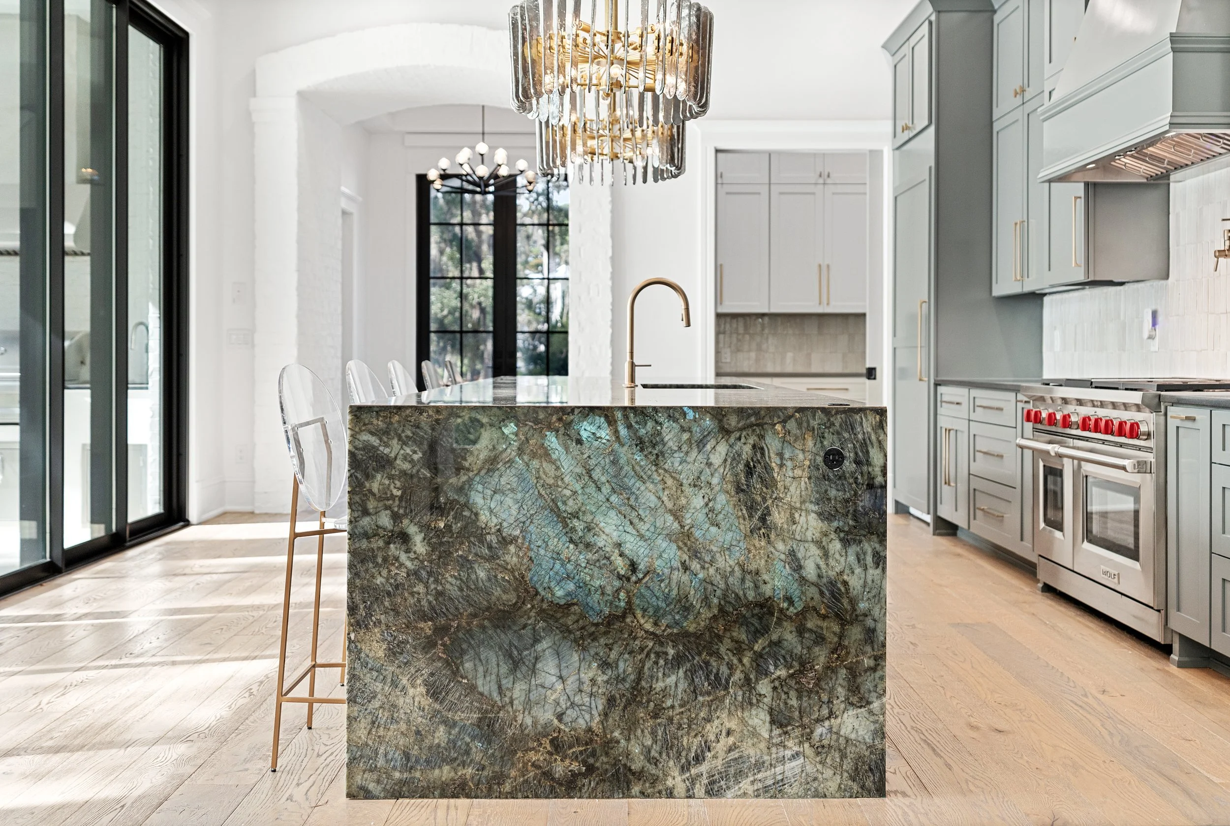 Modern kitchen with a large island featuring a natural stone countertop, stainless steel appliances, and light gray cabinets. - Real estate photography in 30A, Destin, and Panama City Beach by Matt Jozwiak
