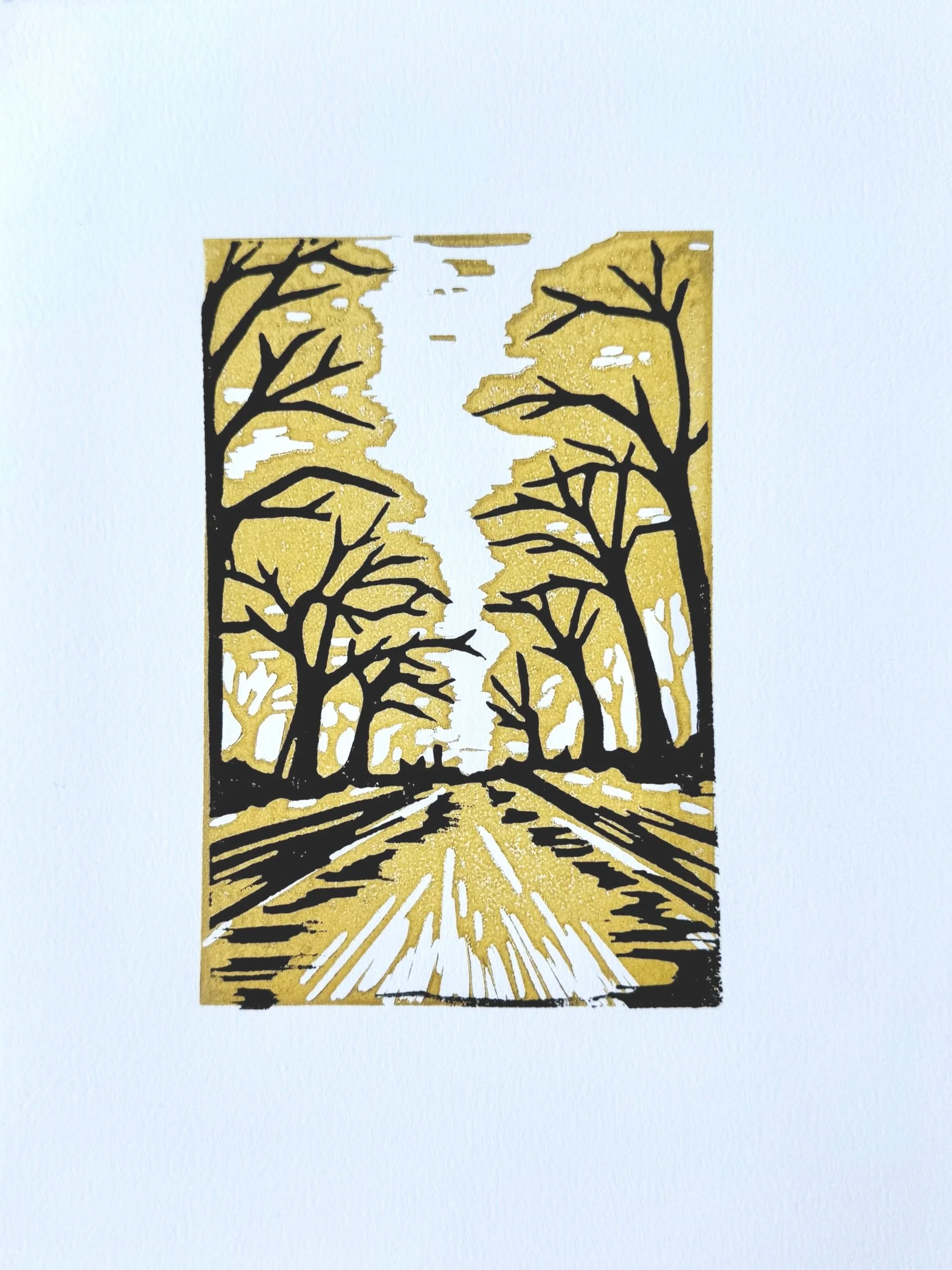 A paper cut-out with a silhouette of trees and a pathway, featuring a gold background and black details.
