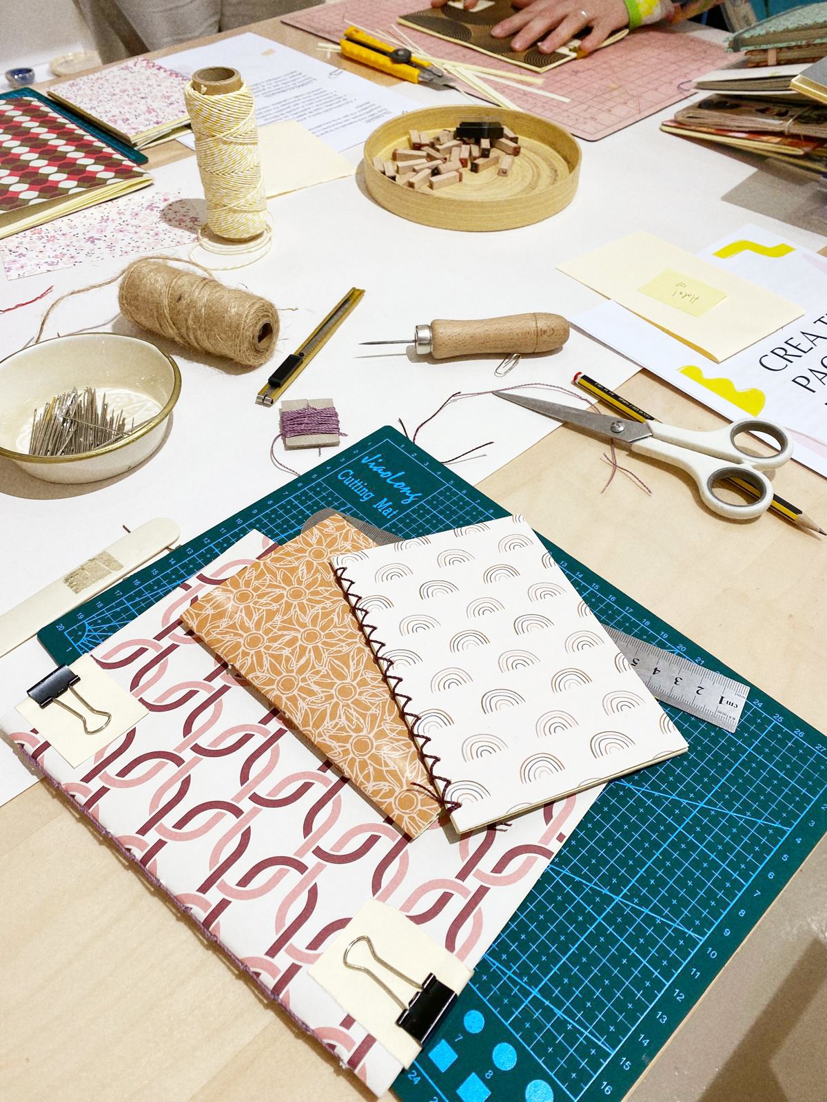 Mesa de trabajo con telas, tijeras, hilo, canutillos y otros materiales textiles para manualidades.