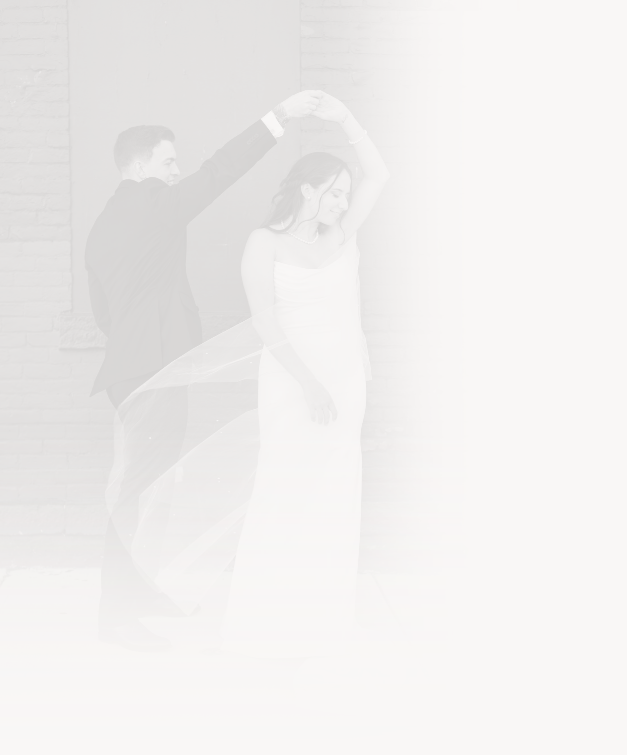 A bride and groom dancing, with the groom holding the bride's hand above her head as they dance together.