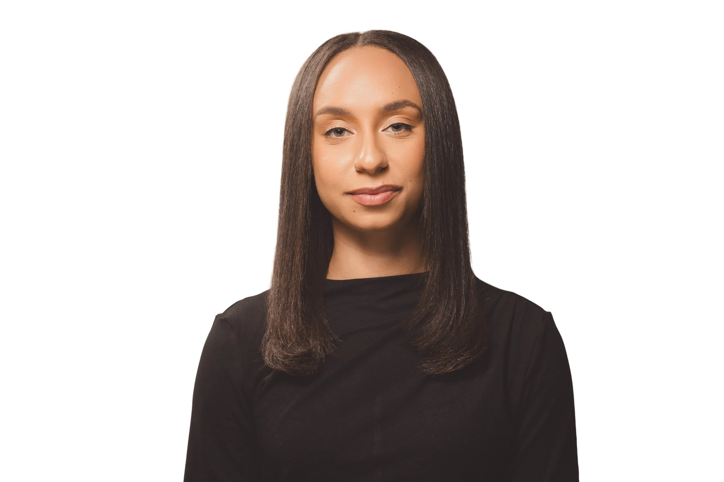 A woman with straight brown hair wearing a black top, looking at the camera with a neutral expression, standing against a plain white background.