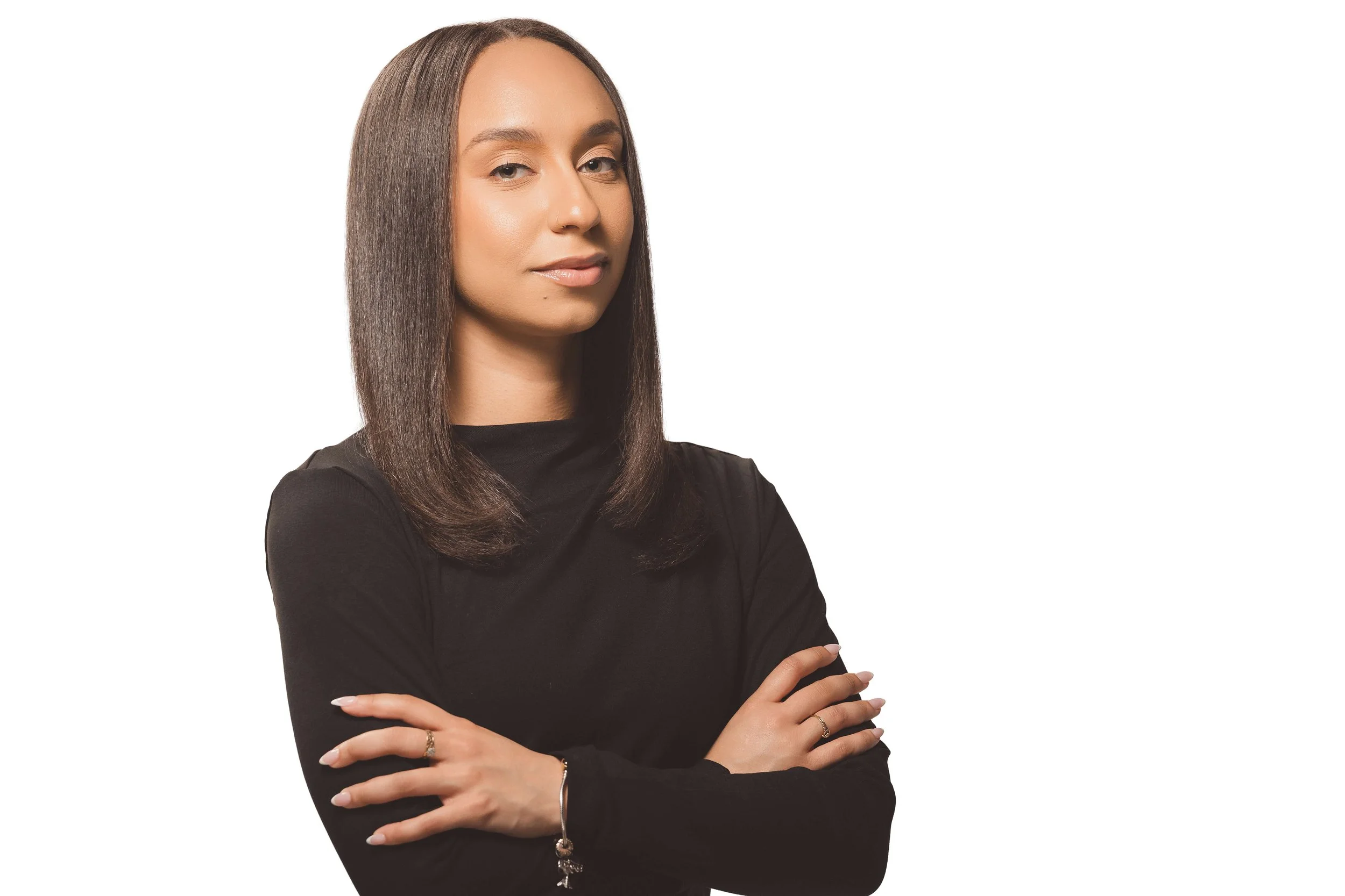 Portrait of a woman with straight brown hair wearing a black top, arms crossed, against a white background.