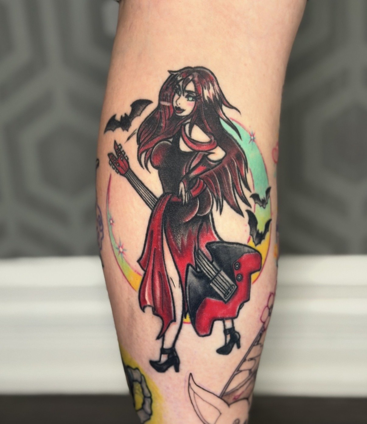 Tattoo of a cartoon witch Thornn from The Hex Girls (Scooby Doo) with long red hair, black dress, and high heels, standing with a confident pose, surrounded by bats and a rainbow background.