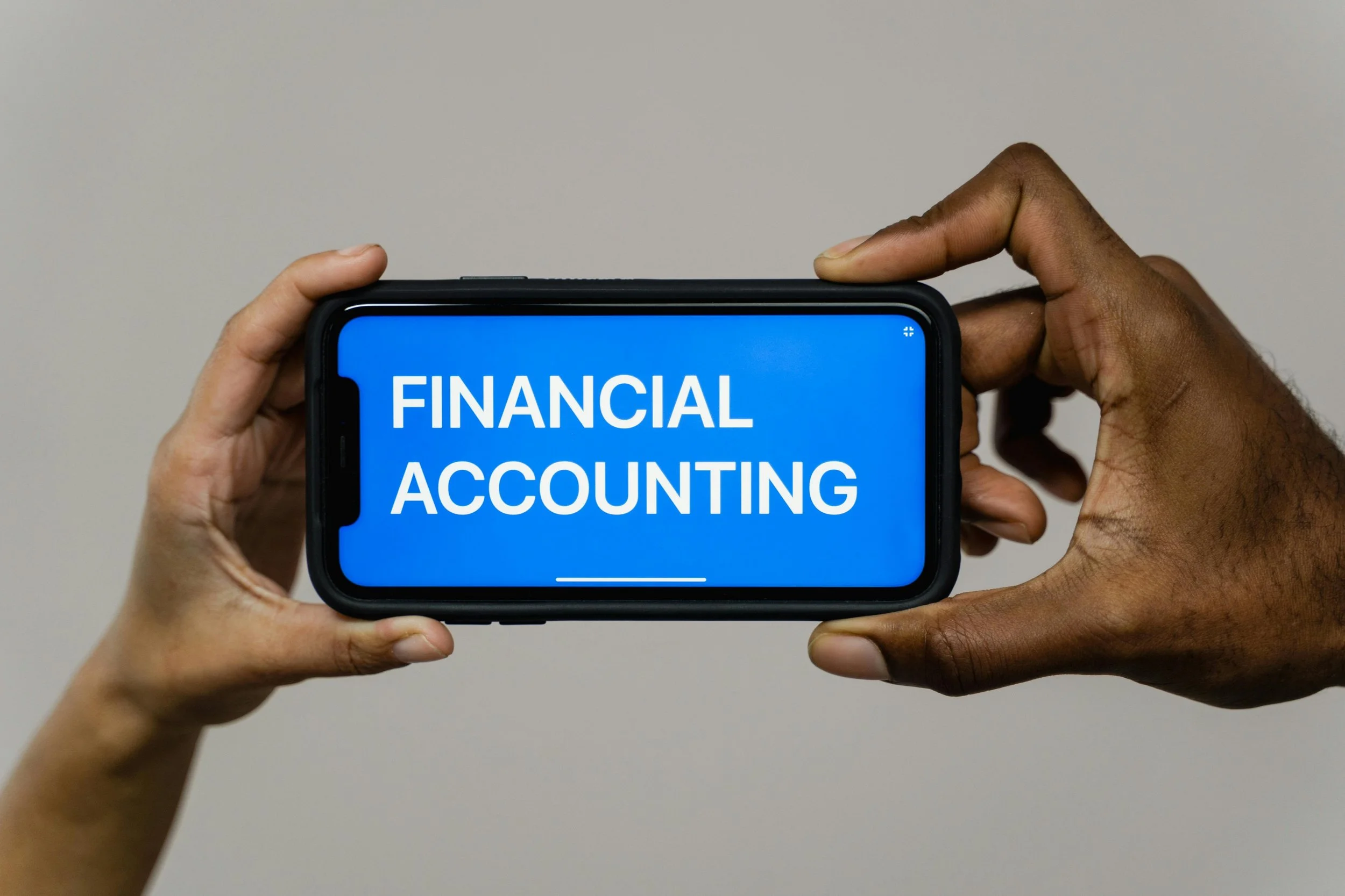 Two hands holding a smartphone displaying the words 'Financial Accounting' on the screen.