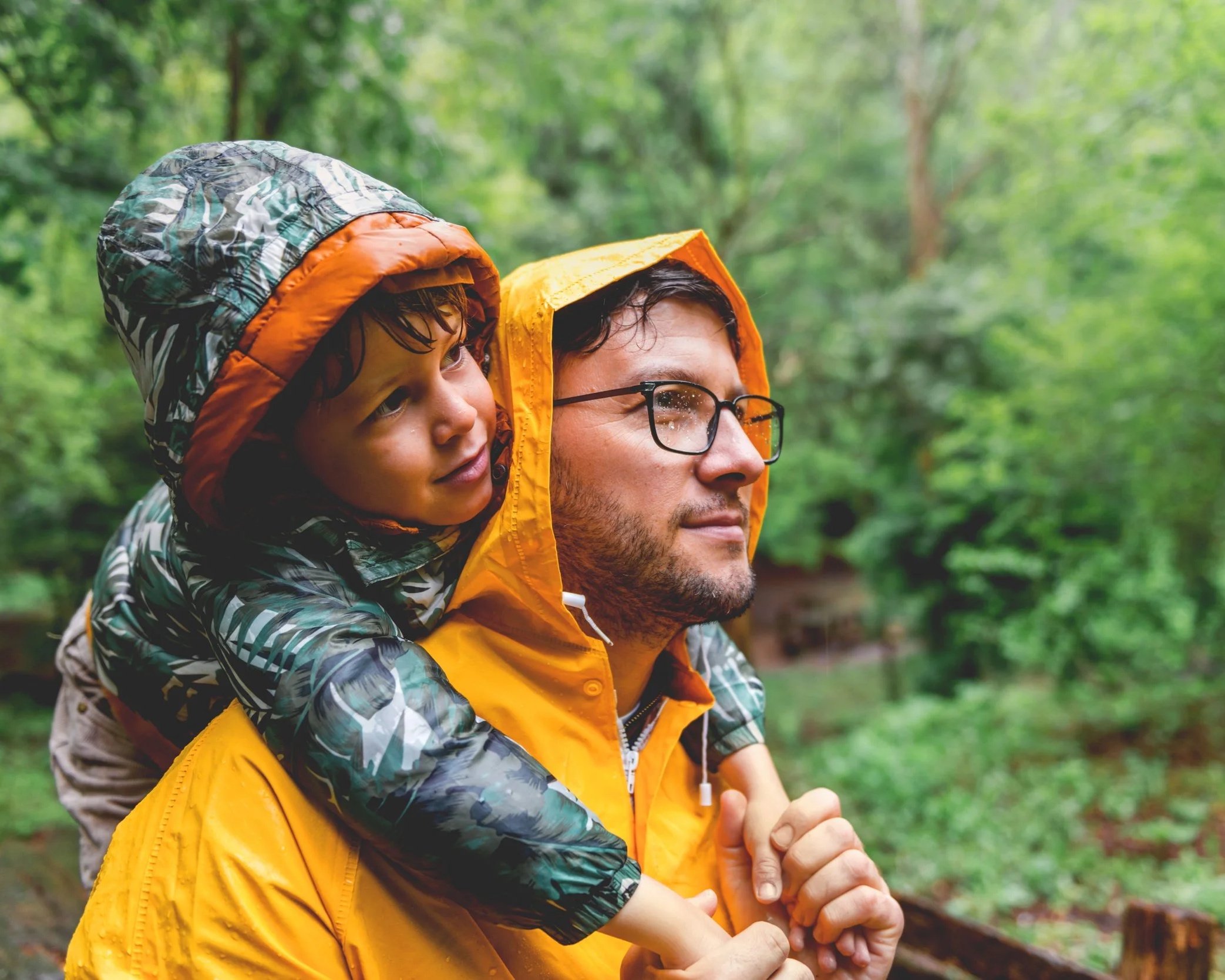Father and child hiking in the rain