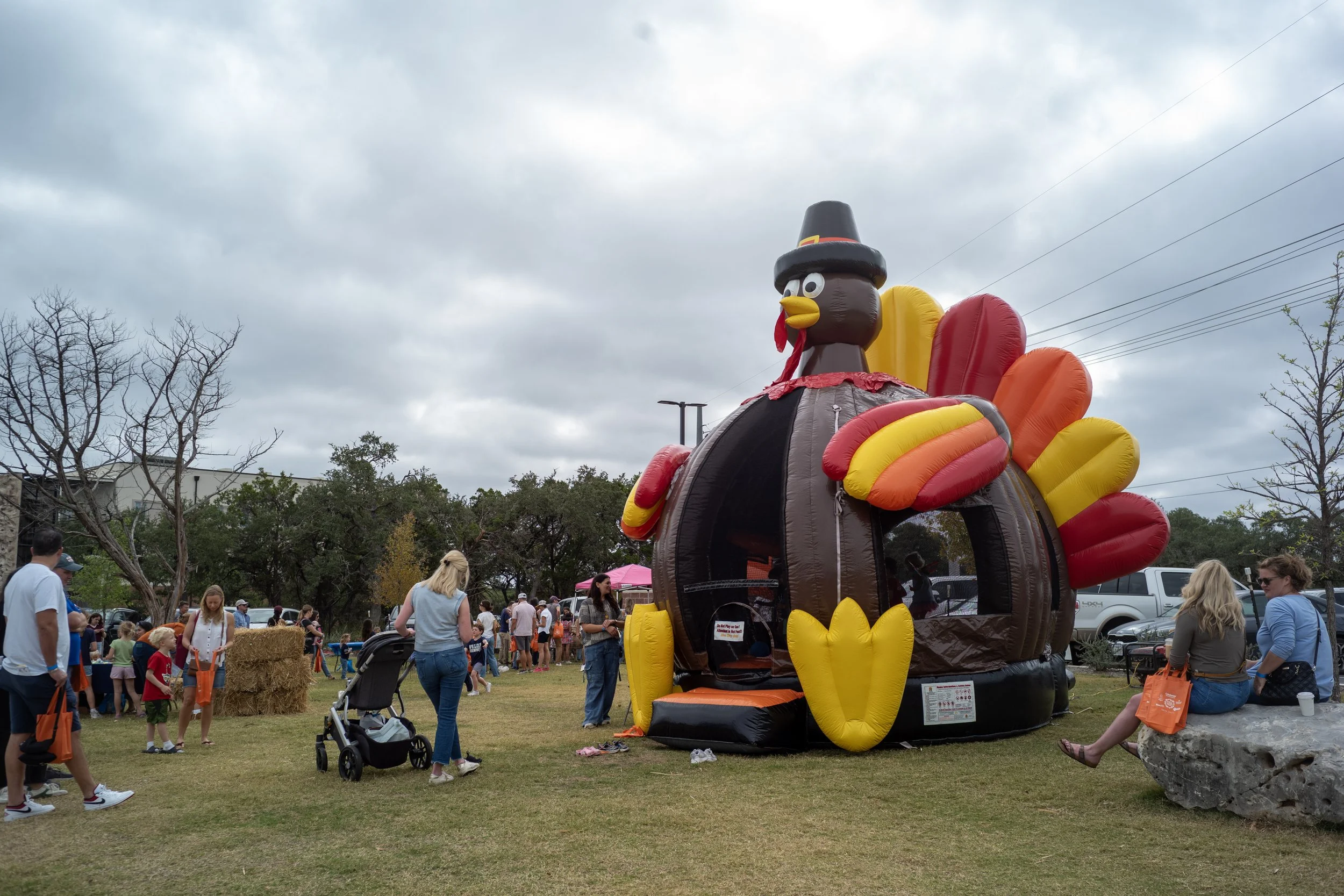 People gathering at an outdoor event with a large inflatable turkey.