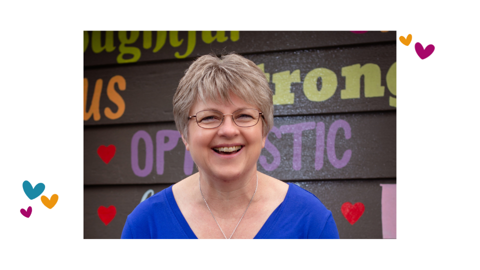 Dr. Melanie Beingessner, baby massage instructor, standing in front of a word wall supporting parents in learning baby massage at home