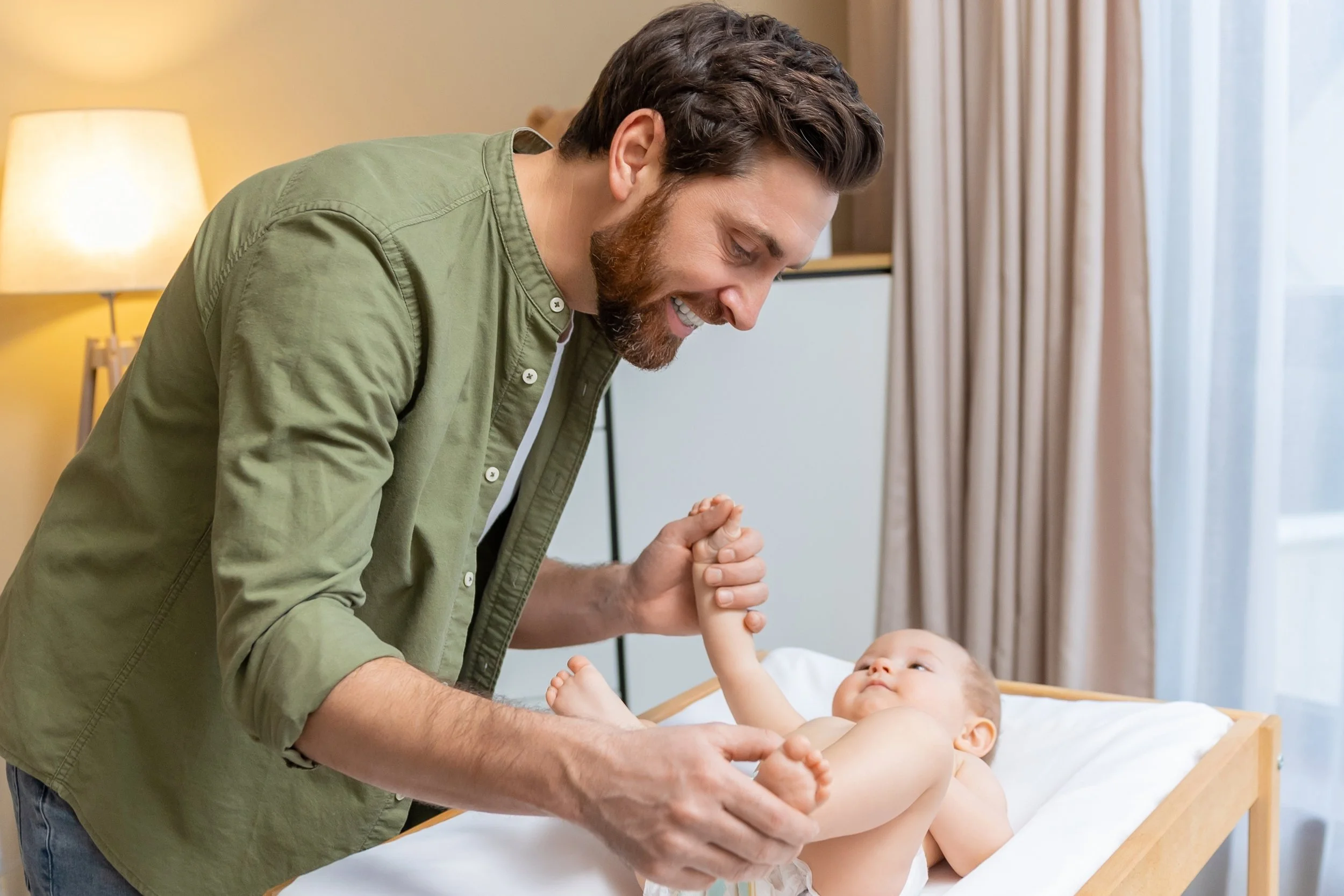 Father gently massaging Baby, showing calm connection and bonding through baby massage