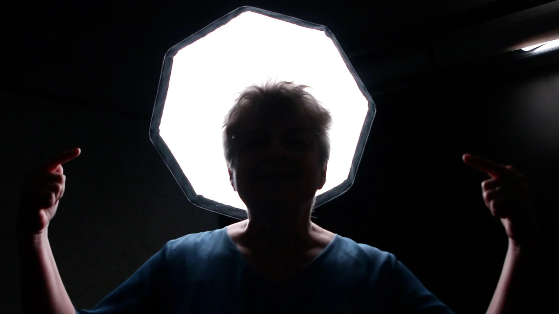 Dr. Melanie Beingessner demonstrating backlighting in a baby massage setup, showing how overhead lighting affects Baby’s ability to see the caregiver’s face