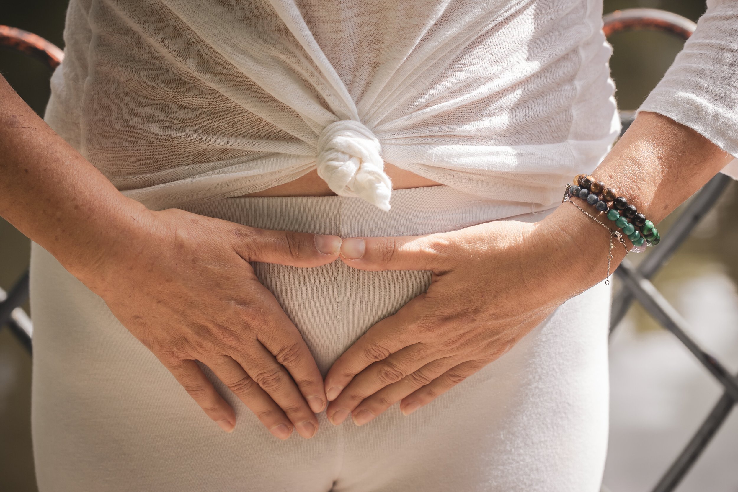 The storefront of a kinesiotherapy clinic with large glass doors, the word 'KINESITHERAPIE' displayed above, and various health-related words like 'PILATES,' 'SPORT,' and 'EFFORT' written on the windows. There is greenery in front of the shop and an apartment or office building above.