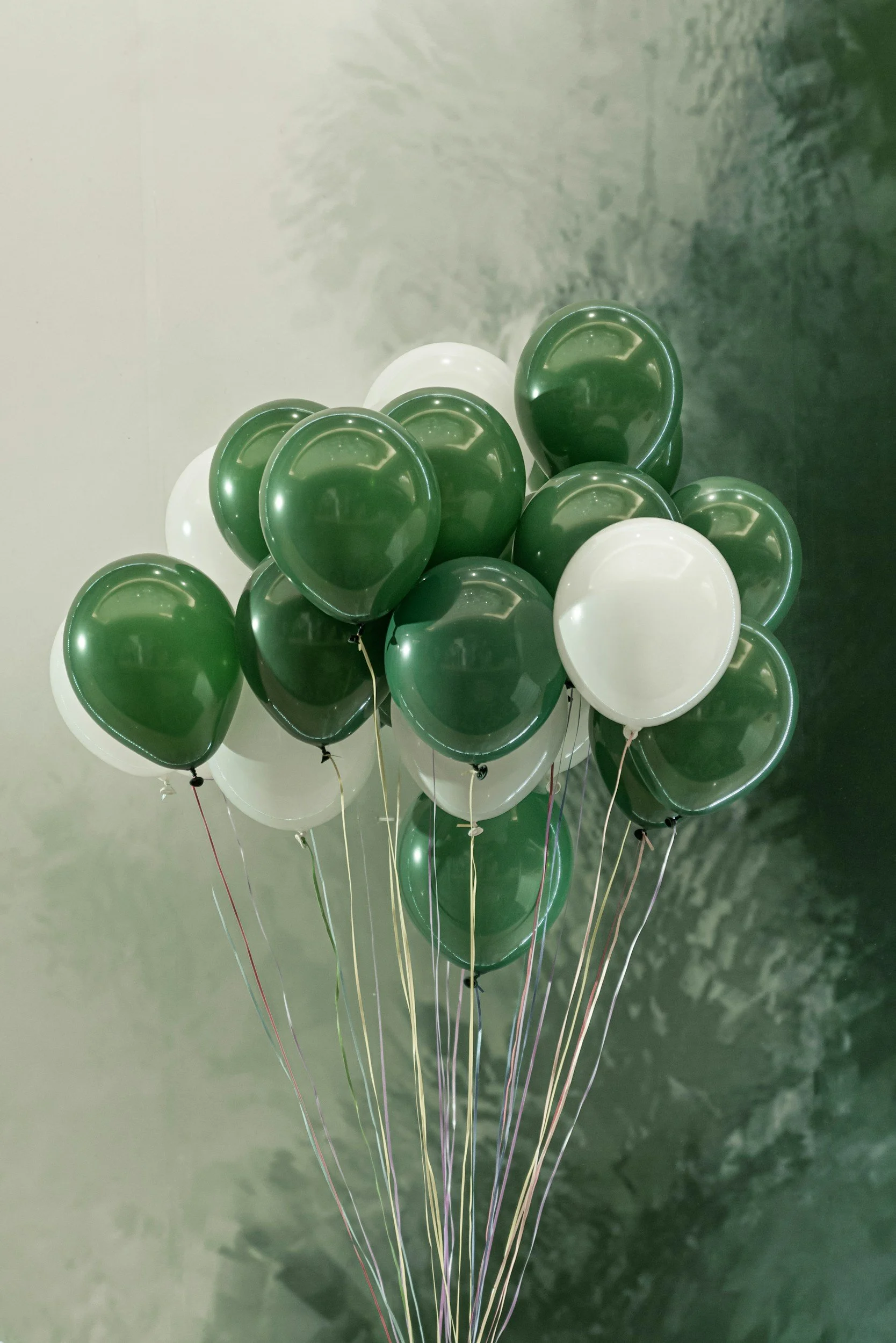 A bouquet of green and white balloons