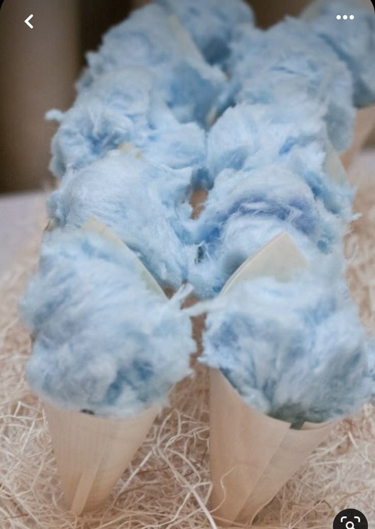 Close-up of blue cotton candy on wooden cones, on a bed of shredded paper.