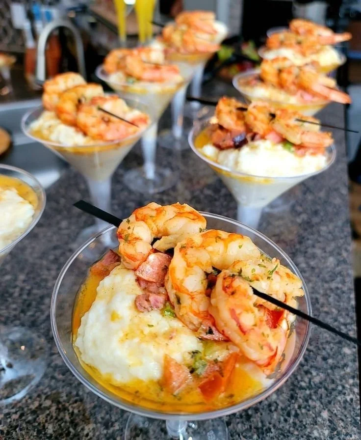 Seafood cocktails with shrimp, bacon, and vegetables served in glass bowls on a granite table.