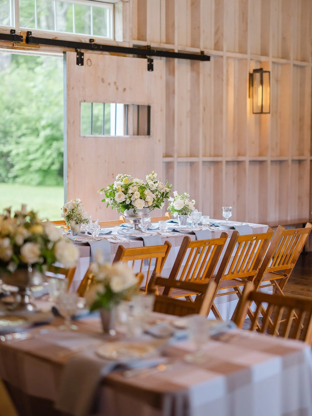 A decorated dining table with white flower centerpieces in a rustic wooden interior, possibly for a wedding or event.