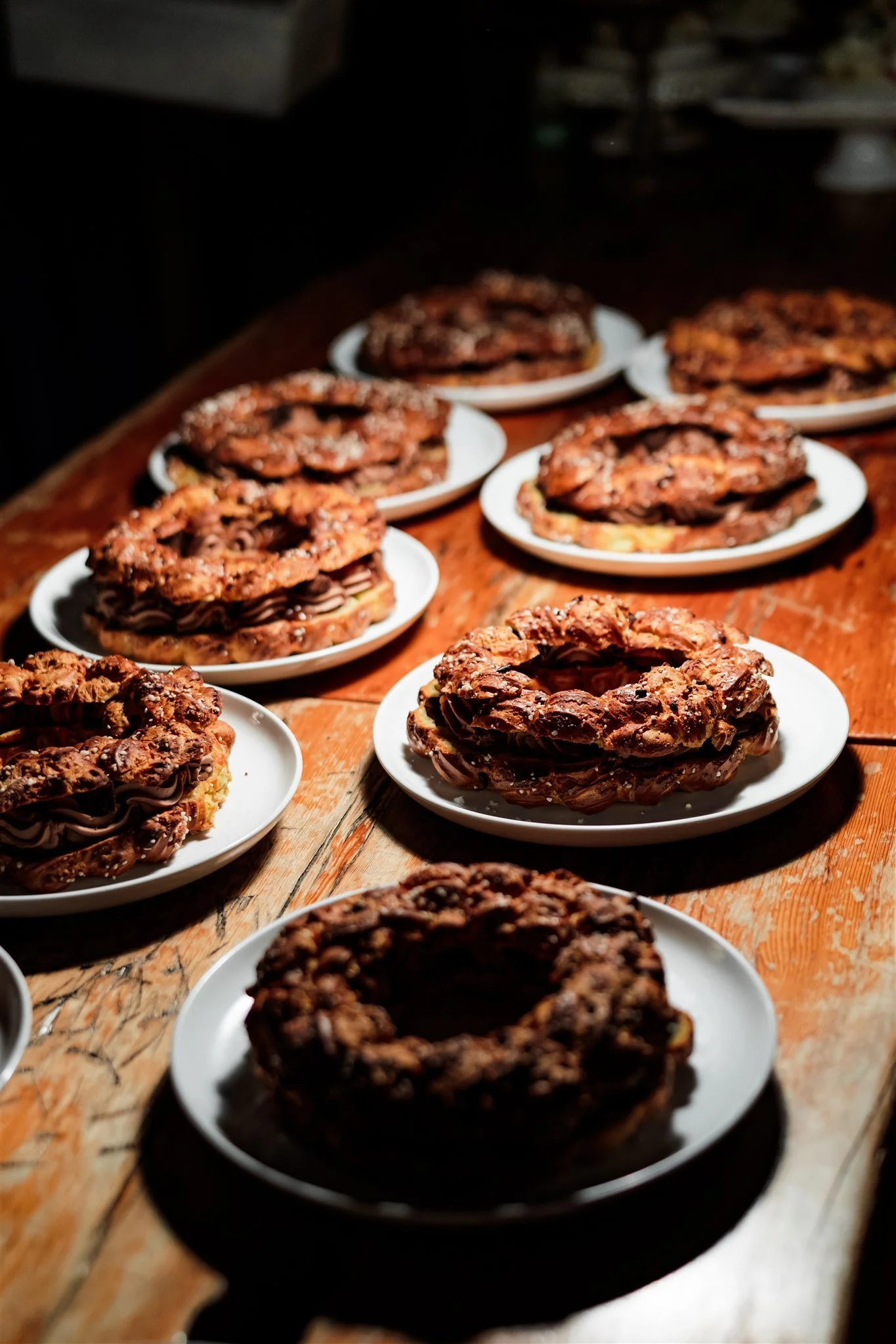 Multiple plates with chocolate cookies placed on a wooden table, with a dark background.