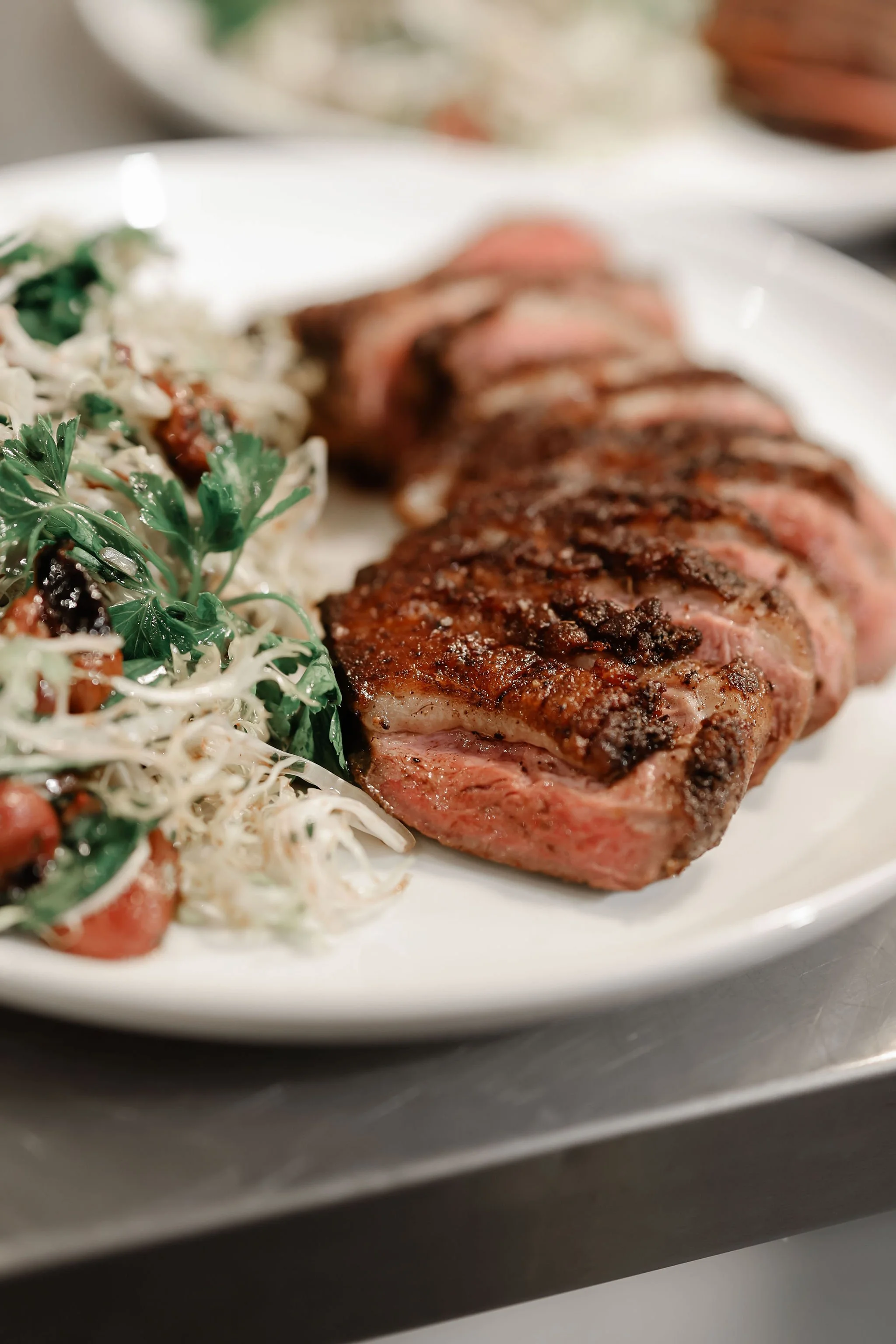 Close-up of a grilled steak served with a side salad on a white plate.