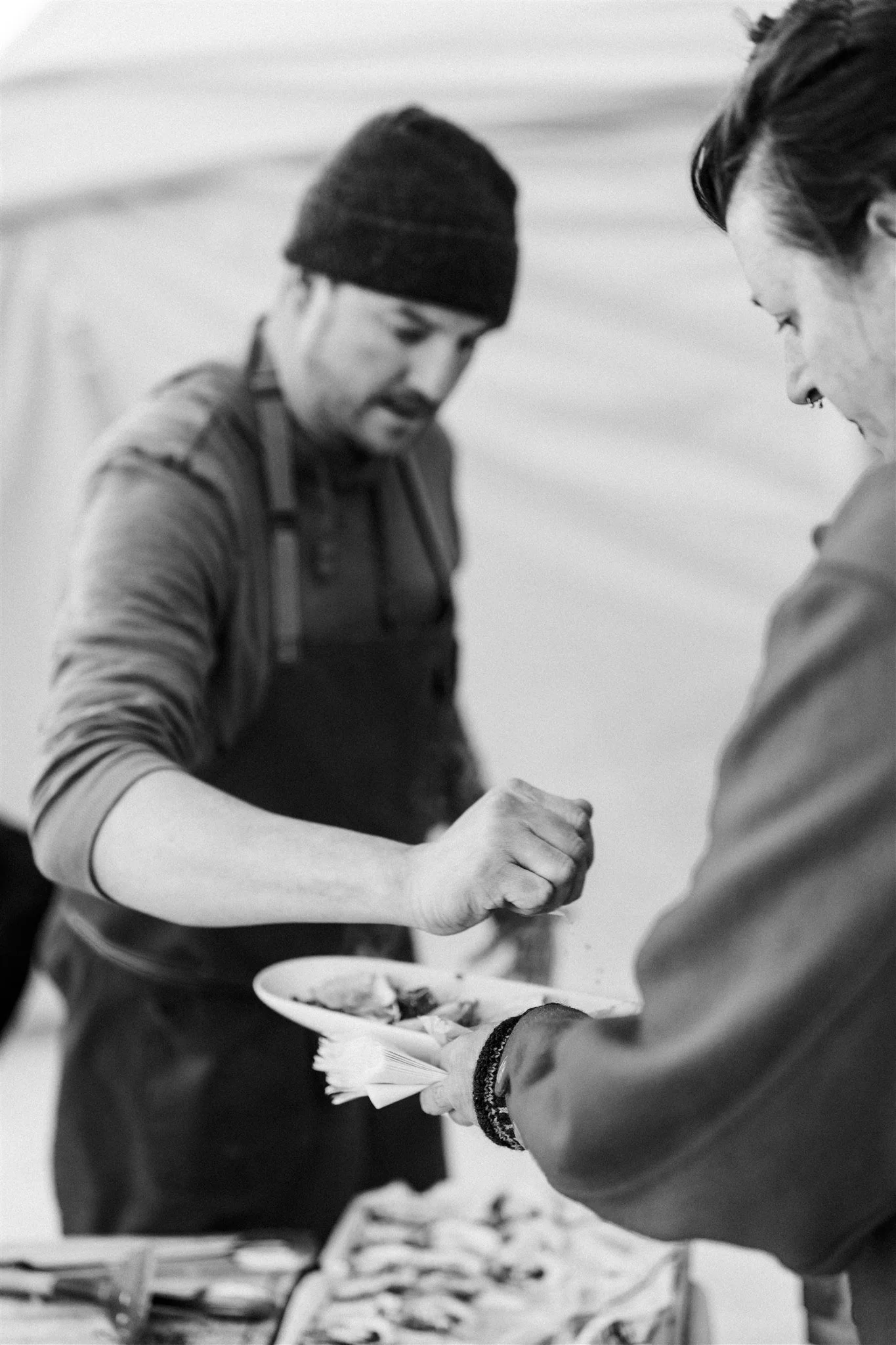 Two people serving food at a buffet.