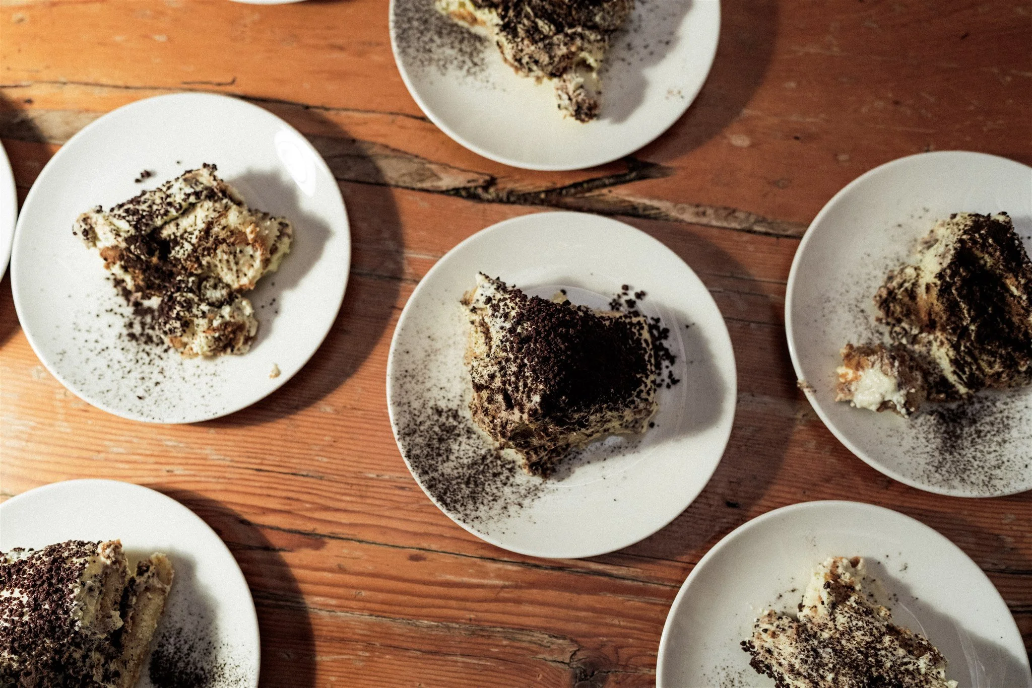 Multiple plates with slices of Oreo cake topped with crumbled Oreos on a wooden table.