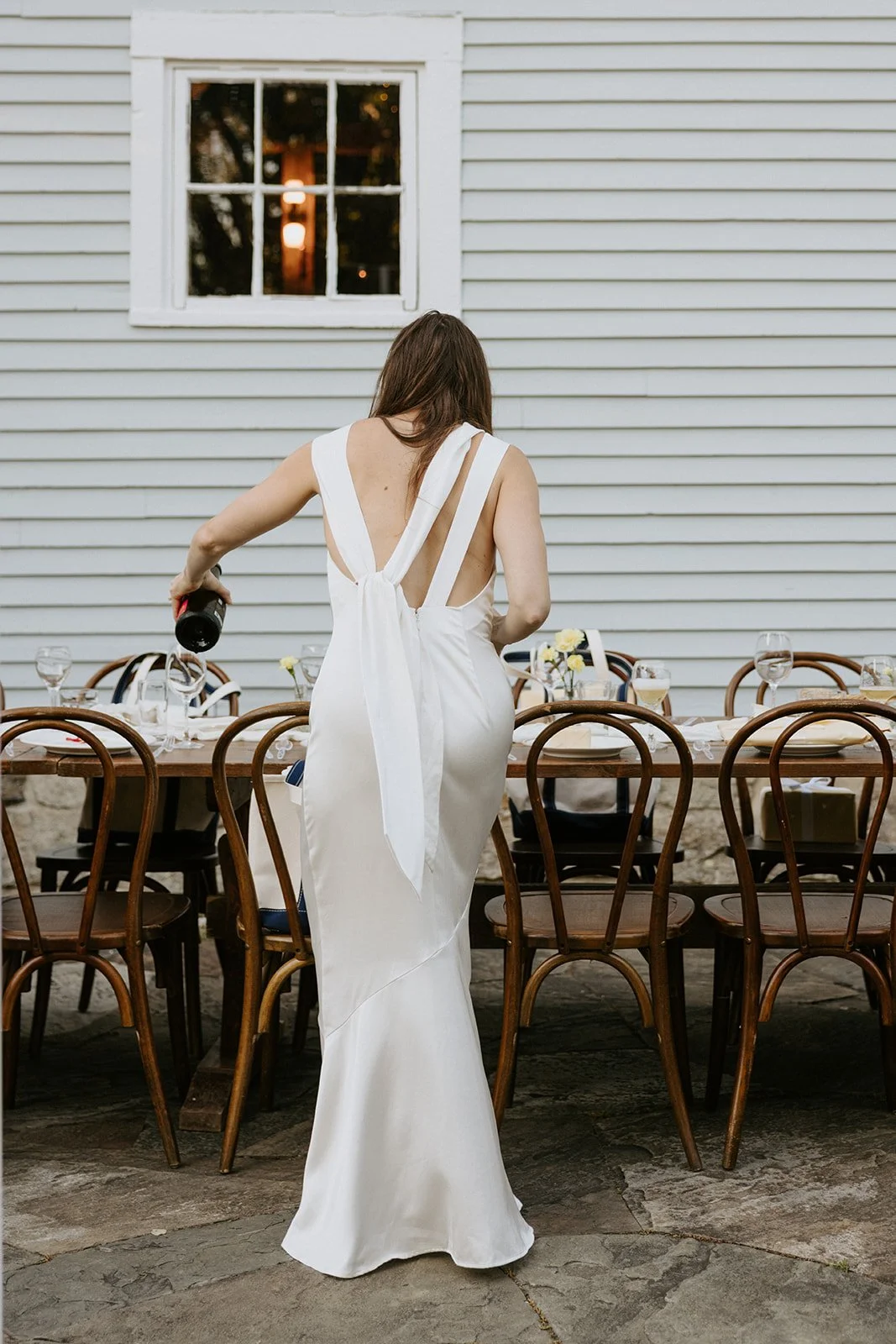 Bride white dress pouring wine at rehearsal dinner
