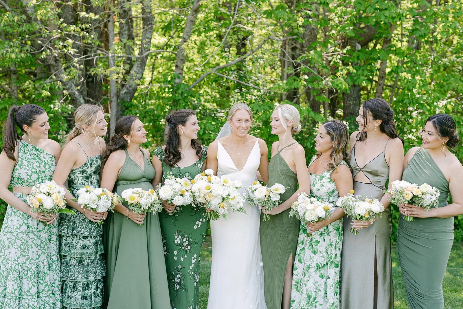 Wedding party gathers around bride with spring florals in Maine