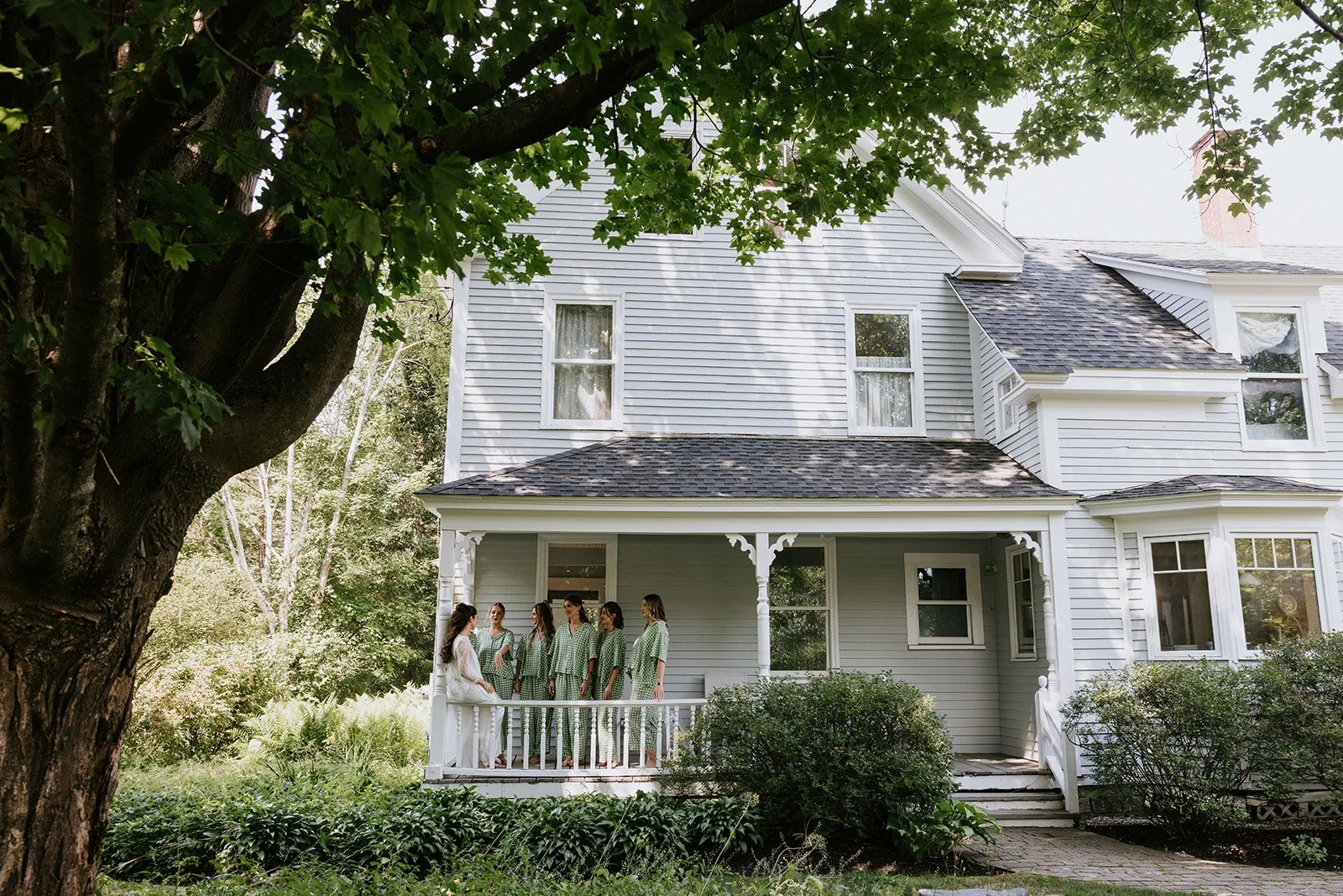 Several women in matching pajamas standing on a house's front porch.