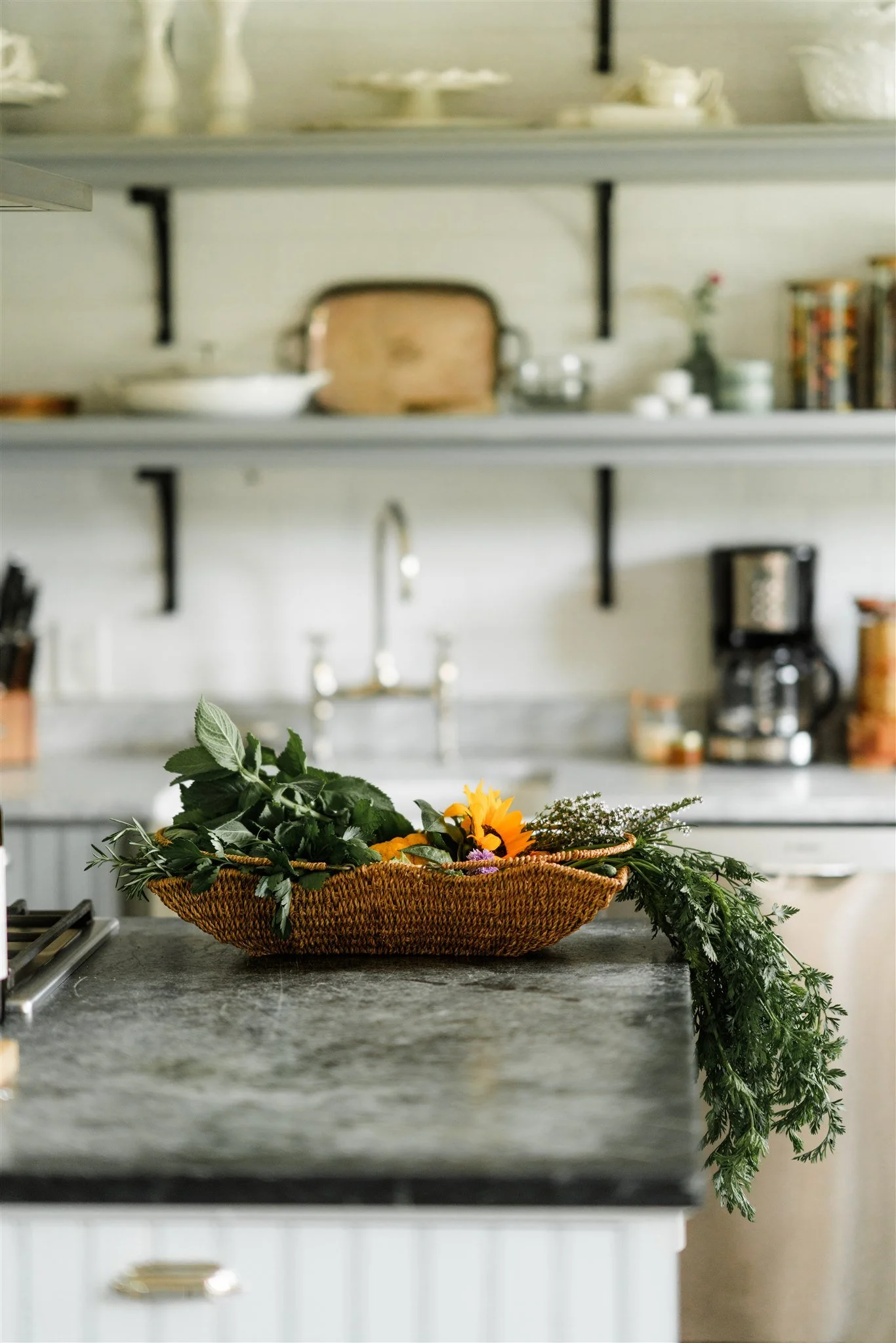 A basket of assorted flowers and greenery on a kitchen island