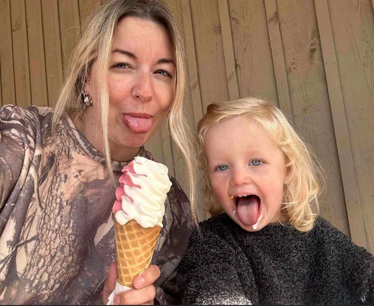Une femme et une jeune fille jouent avec de la glace à l'écoute d'une image, la femme tient une cornet avec une boule de glace à la vanille et à la fraise, toutes deux ayant la langue sortie.