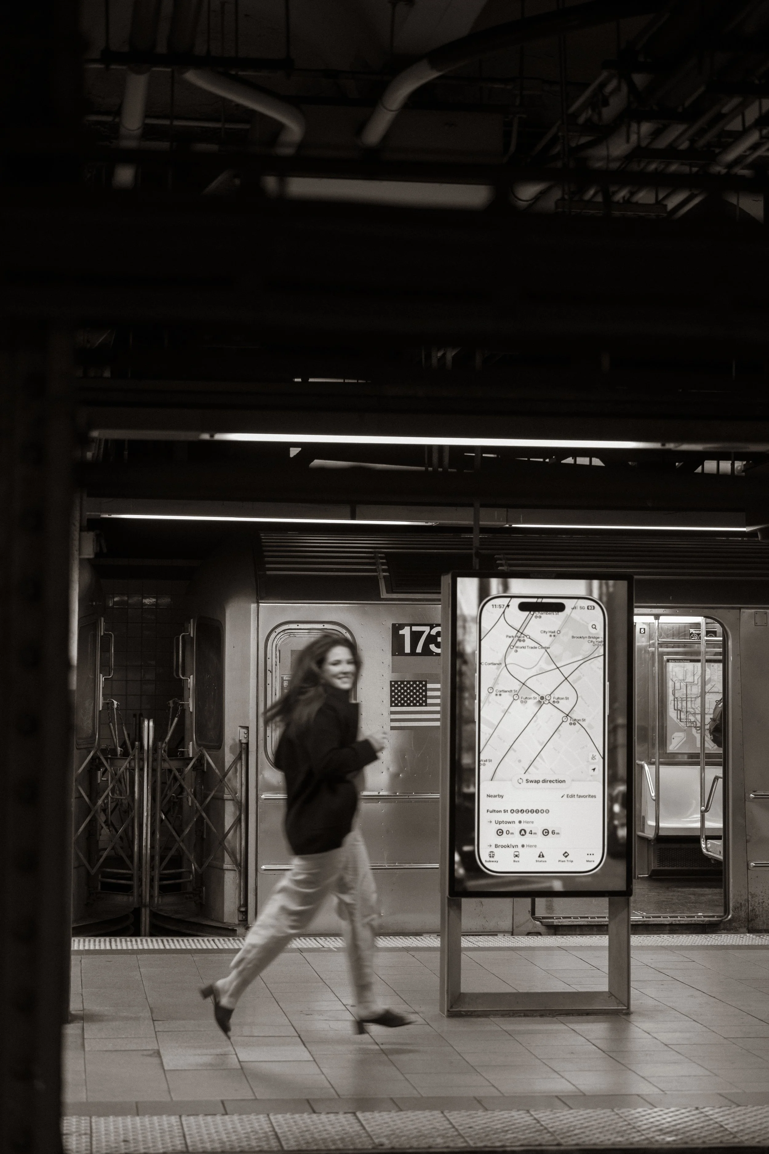 A woman in business attire walking briskly in a subway station, with a train behind her and a digital map display in the foreground.