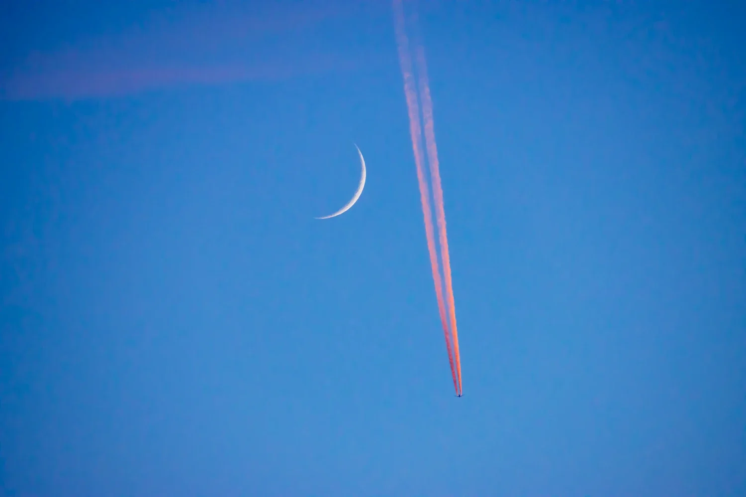 Crescent moon with red plane trail