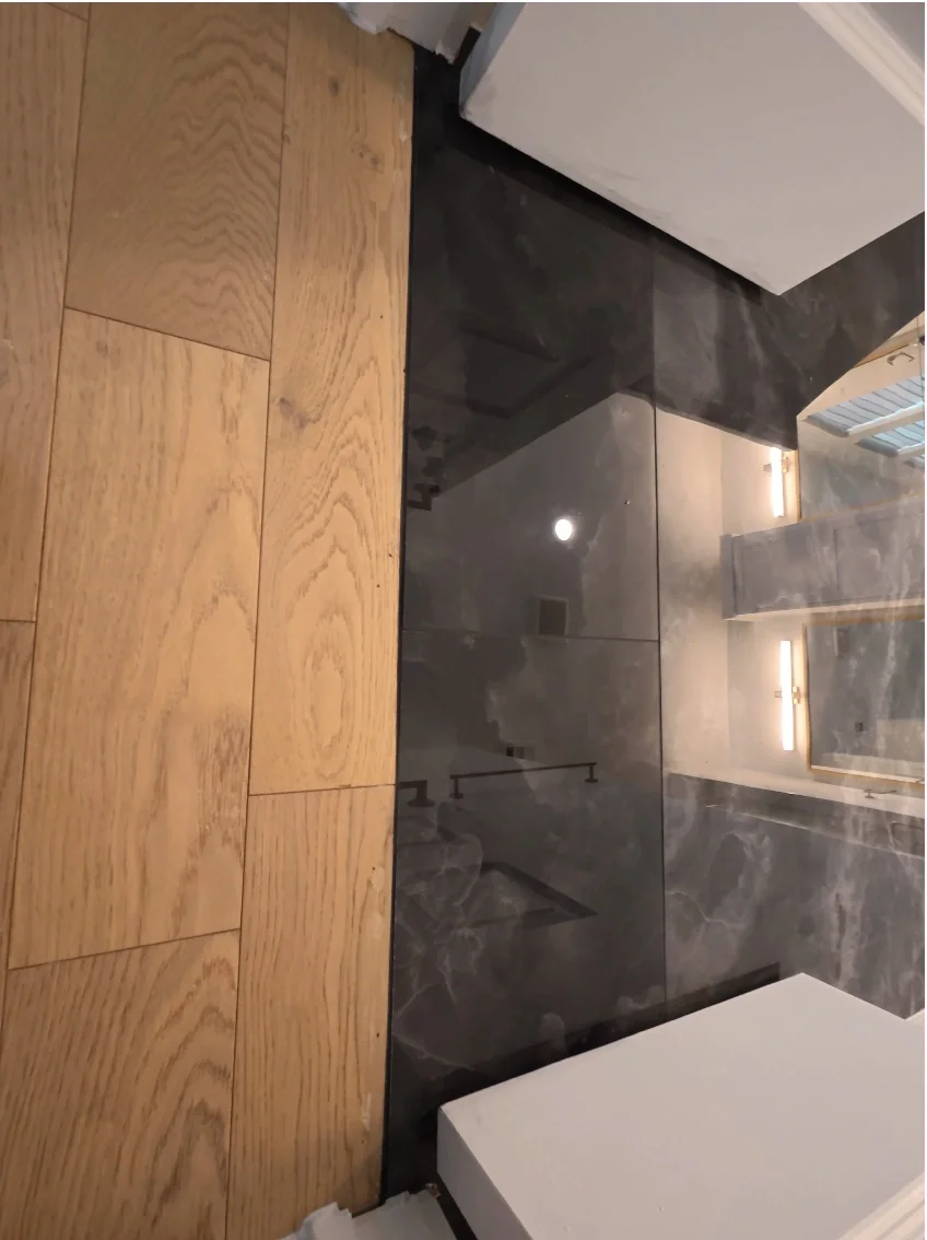 Close-up of a transition between hardwood and marble flooring in a modern interior.