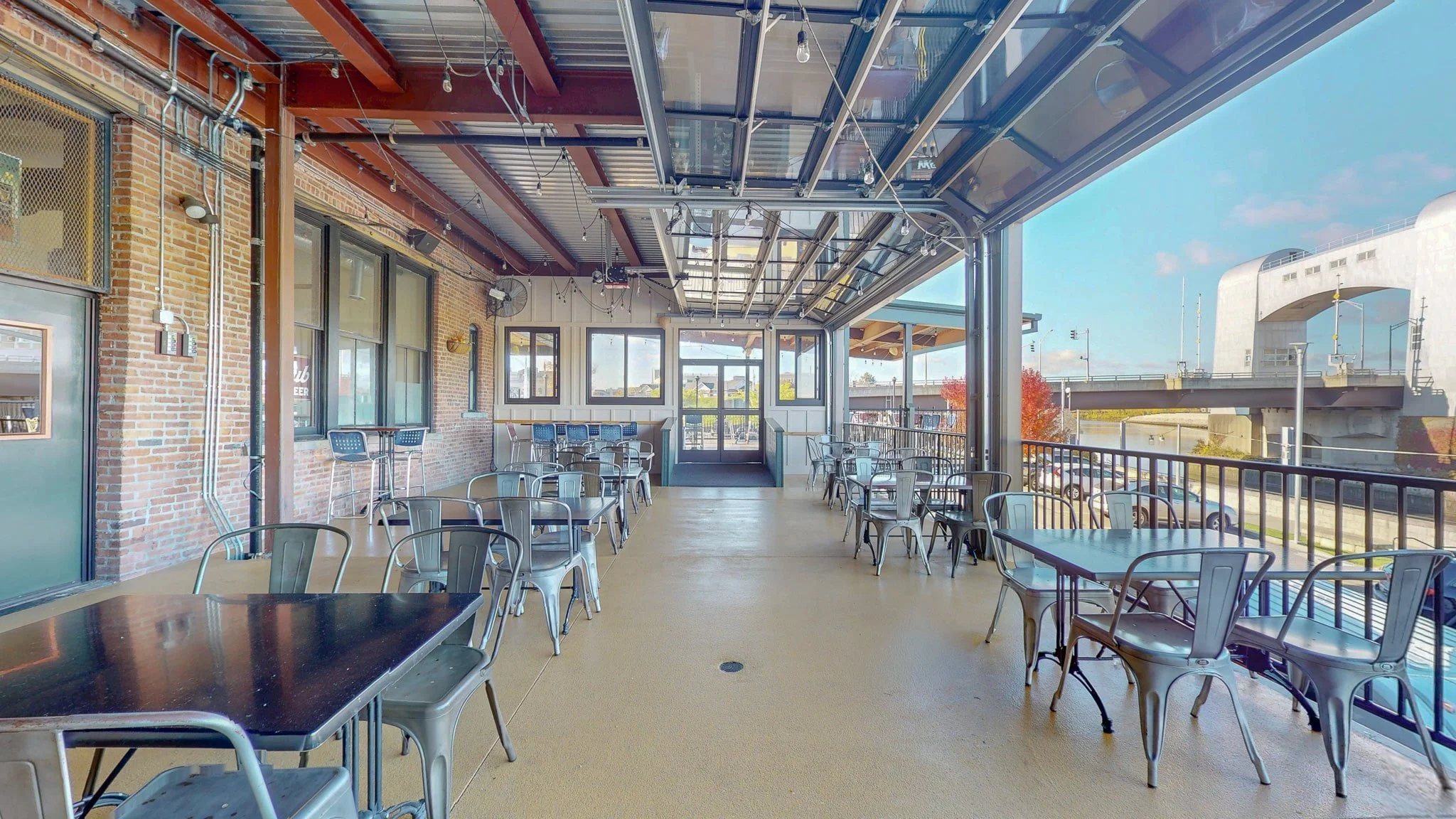 Outodoor seating. Deck, chairs, table, blue sky, Green Island Bridge. 