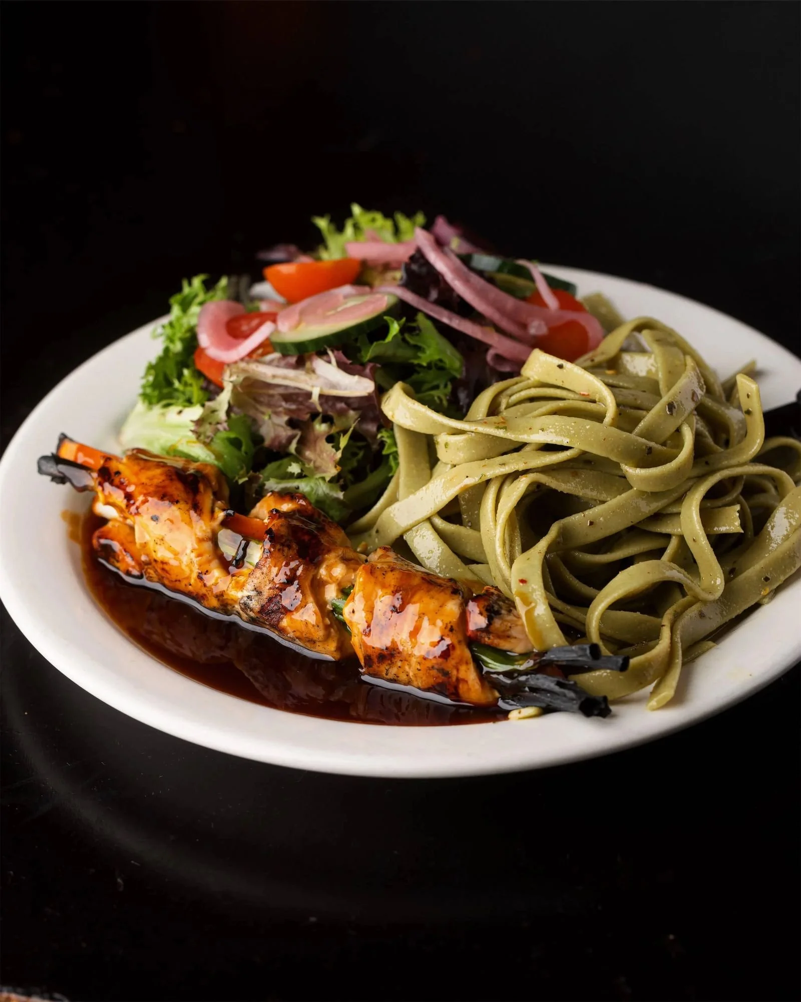 Chicken Teriyaki Dinner at Ryan's Wake: a teriyaki-glazed chicken skewer wrapped around scallions and carrots, with chilled spinach noodles and a side salad with pickled onions.