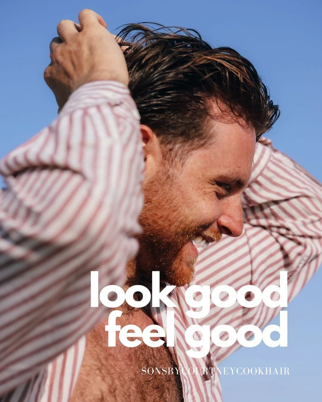 Side profile of a man with dark hair and a beard, smiling and wearing a red and white striped shirt, with a clear blue sky in the background.
