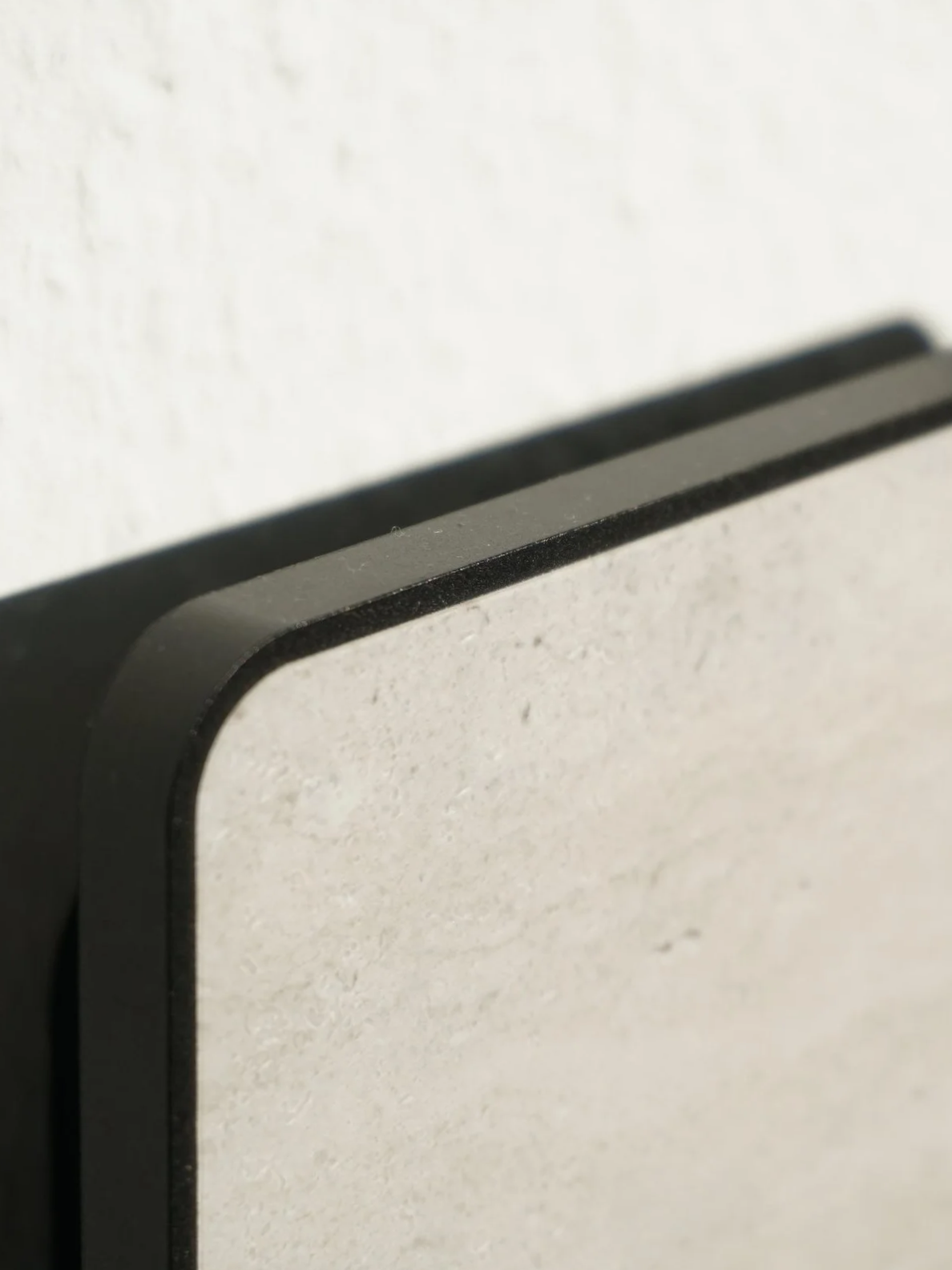 Close-up of a corner of a beige textured front plate, with a black aluminium border.