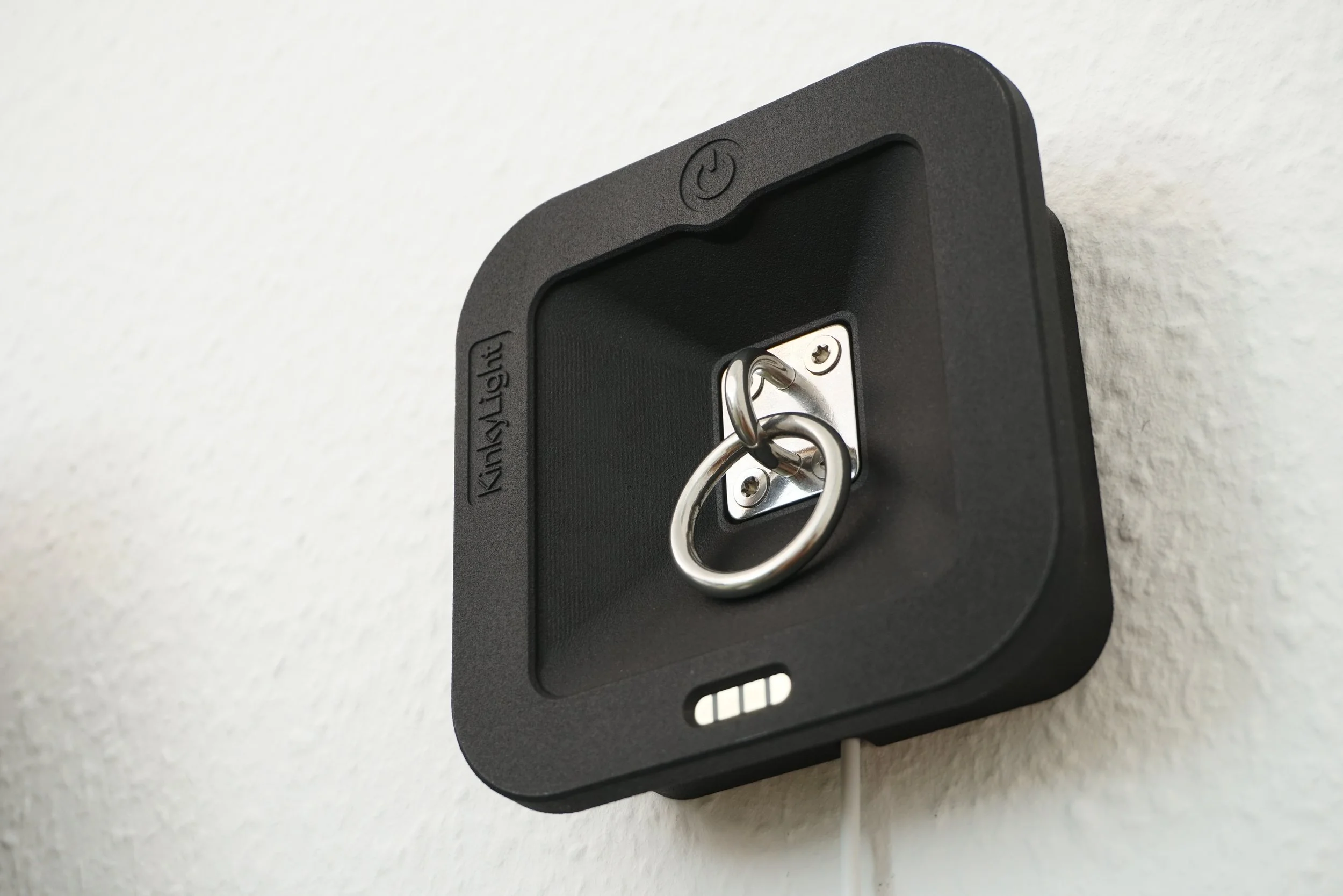 Wall-mounted bedside lamp with a metal ring for key storage mounted on a textured white wall.
