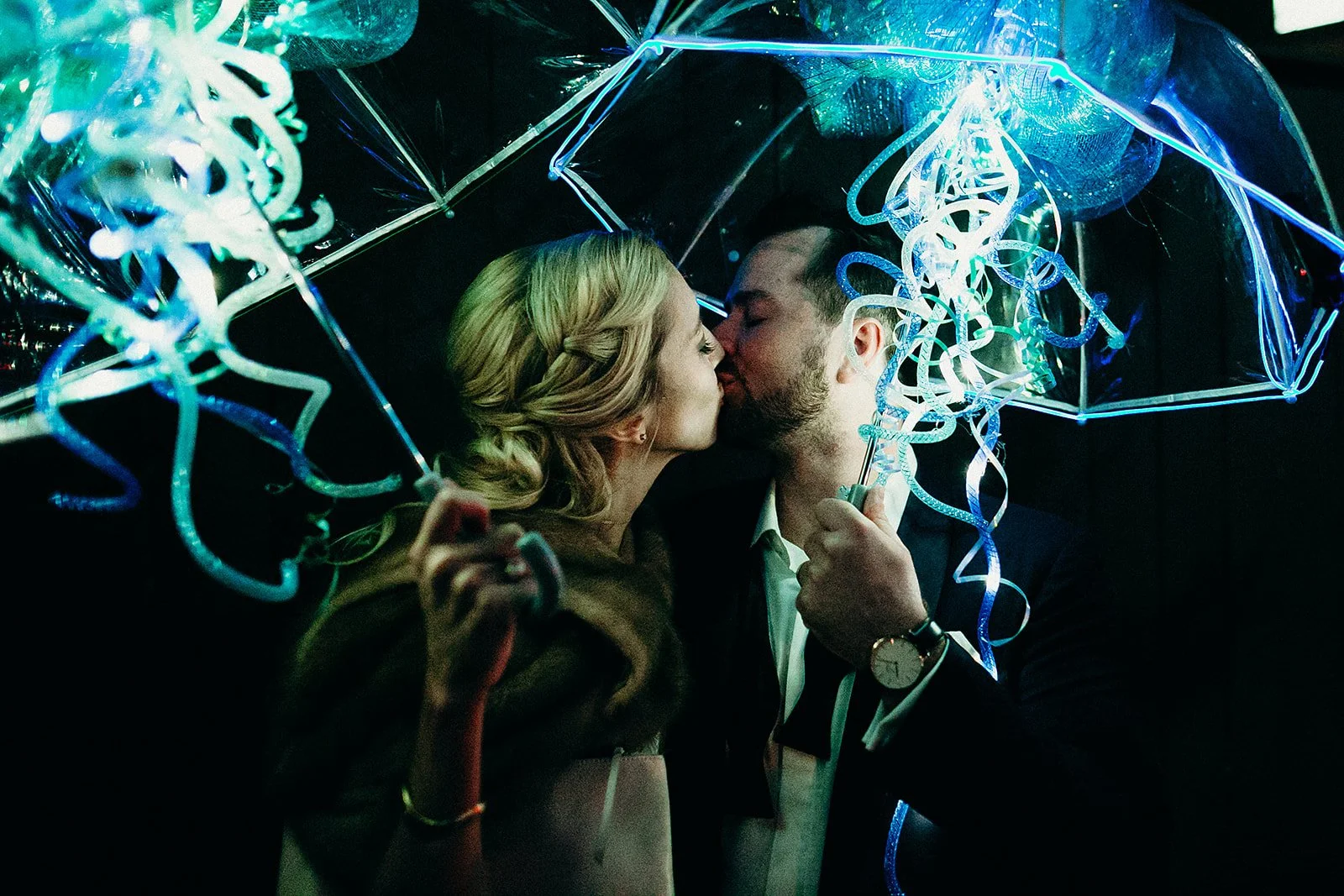 Bride and groom kissing under umbrellas during a second line at Il Mercato the Lower Garden District, New Orleans