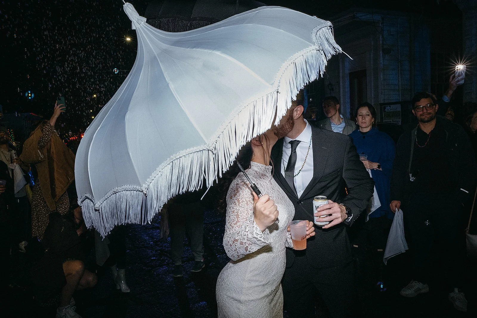 Bride and groom kissing in the street during a second line after their wedding at Hotel Peter & Paul in the French Quarter, New Orleans LA