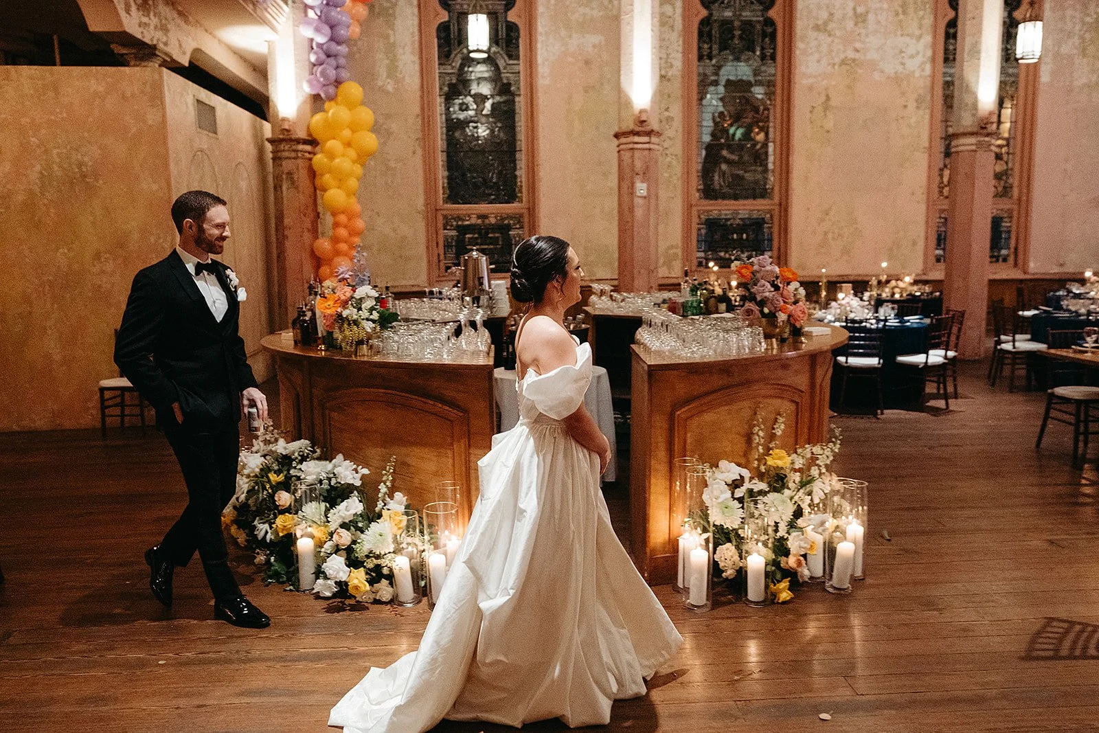 Bride and groom walking into the wedding reception space with flowers and candle lit at Hotel Peter & Paul in Faubourg Marigny, New Orleans