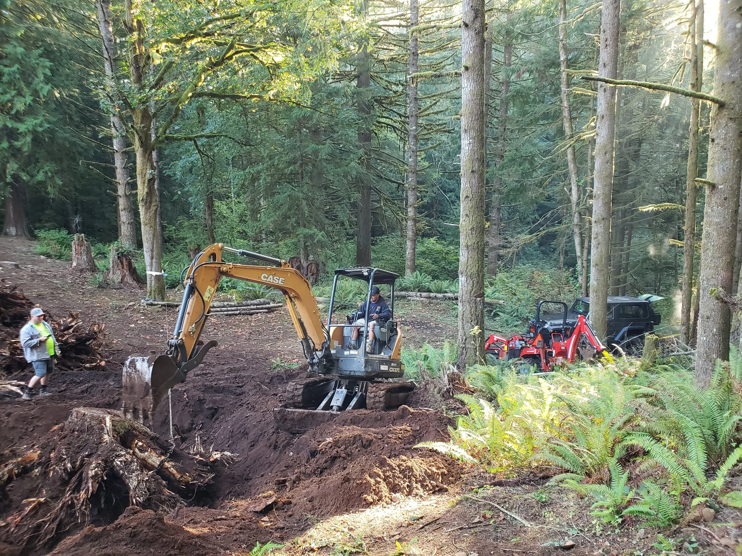 North Woods Tree Service owner pulling a massive stump to clear a forested area beside a property — land clearing | North Woods Tree Service