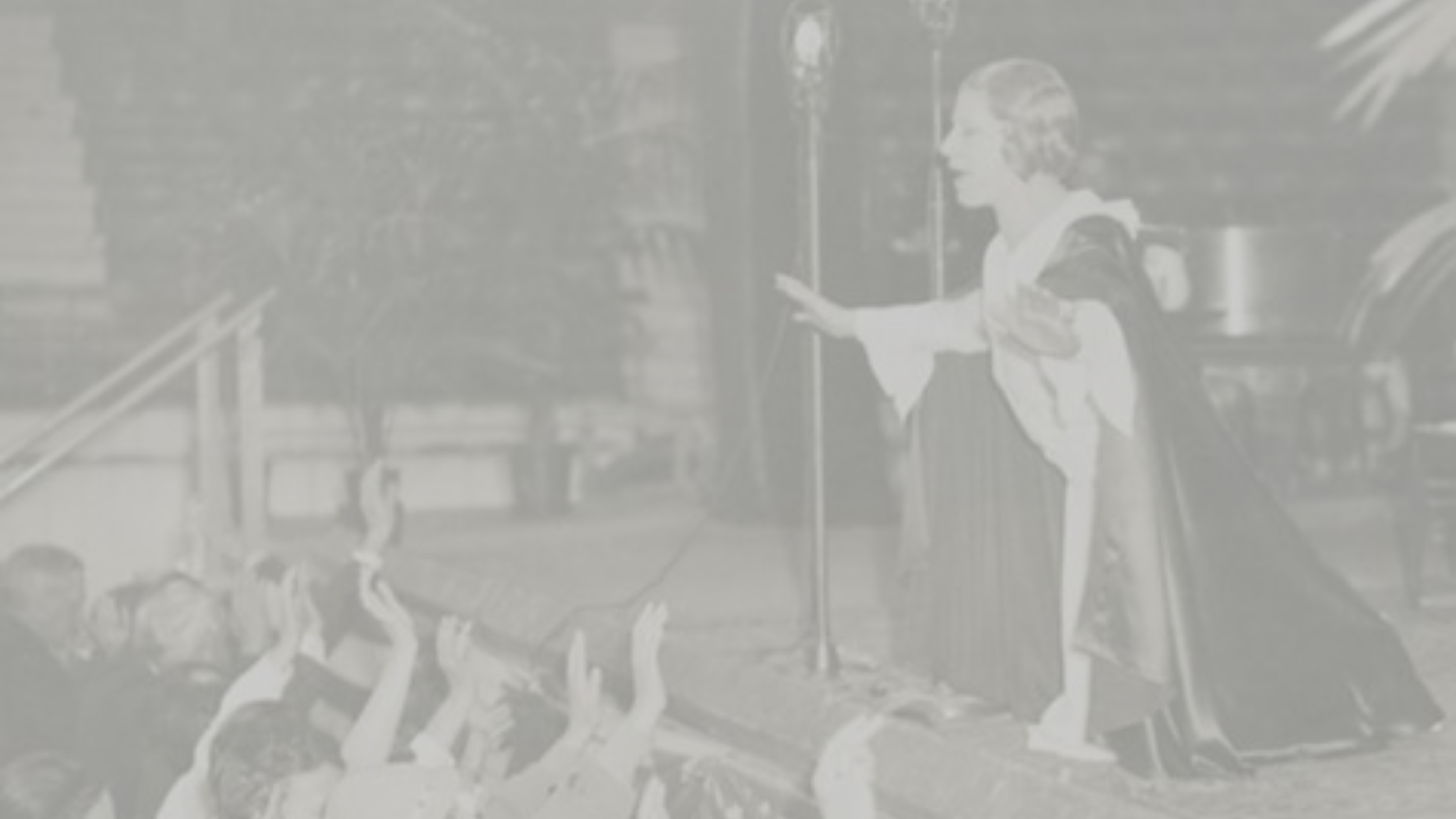 Sister Aimee Semple McPherson preaching outdoors at night, greeting a group of children reaching out to her.