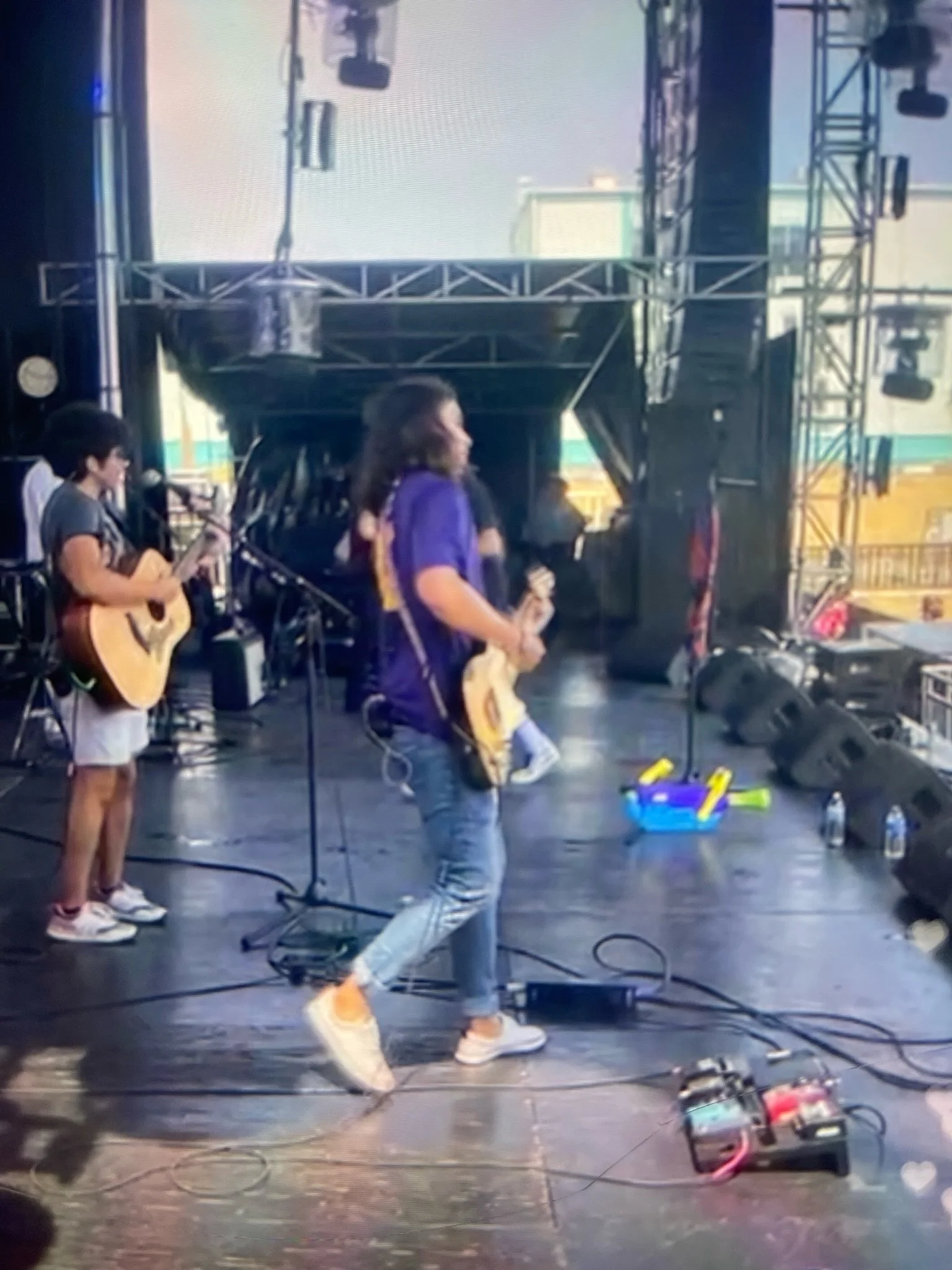 matthew blocha, native american musician performing on stage with musical instruments, one with a guitar and the other with a microphone, during a live outdoor event.