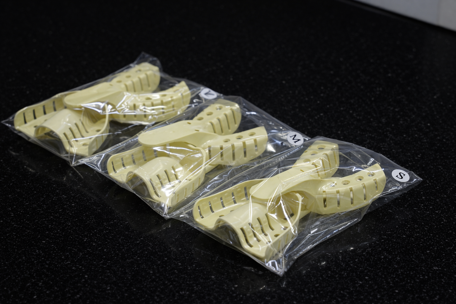 Plastic orthodontic shadows in labeled bags on a black countertop.